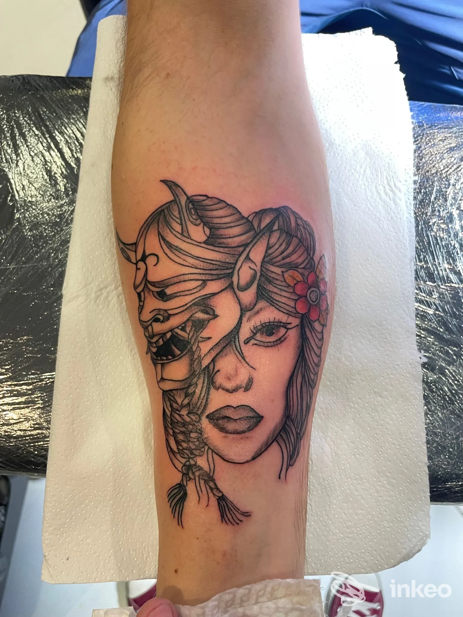 Tatuaggio su avambraccio raffigurante volto femminile con maschera oni, linee nere e tocchi rossi, scatto per _n1kmark_TattooStudio a Calangianus.