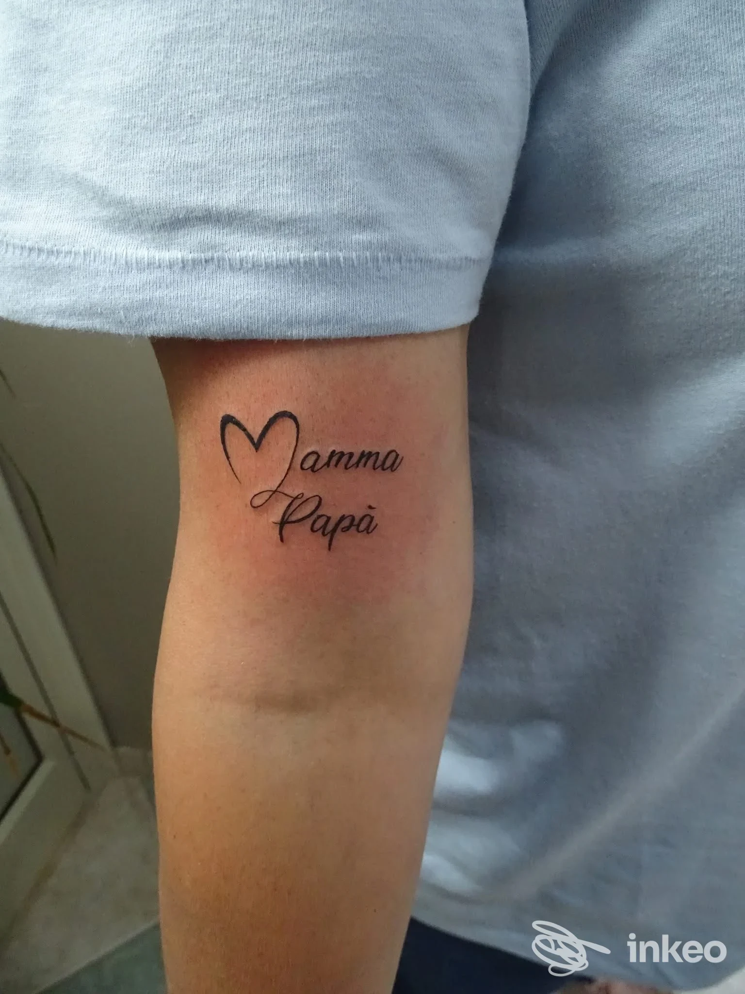 Tatuaggio "Mamma Papà" con cuore stilizzato sul lato interno dell'avambraccio vicino al gomito, fotografia di lavoro di Barraco Design a Marsala.