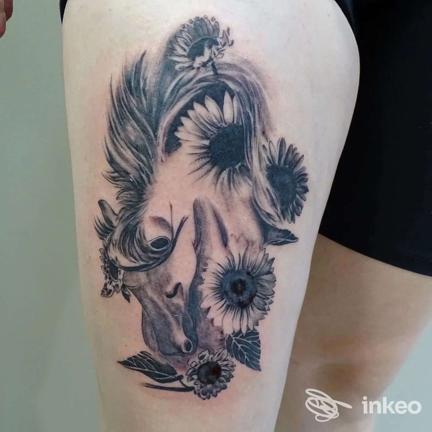 Tatuaggio in bianco e nero su coscia: profilo di cavallo circondato da girasoli, Barraco Design, Marsala.