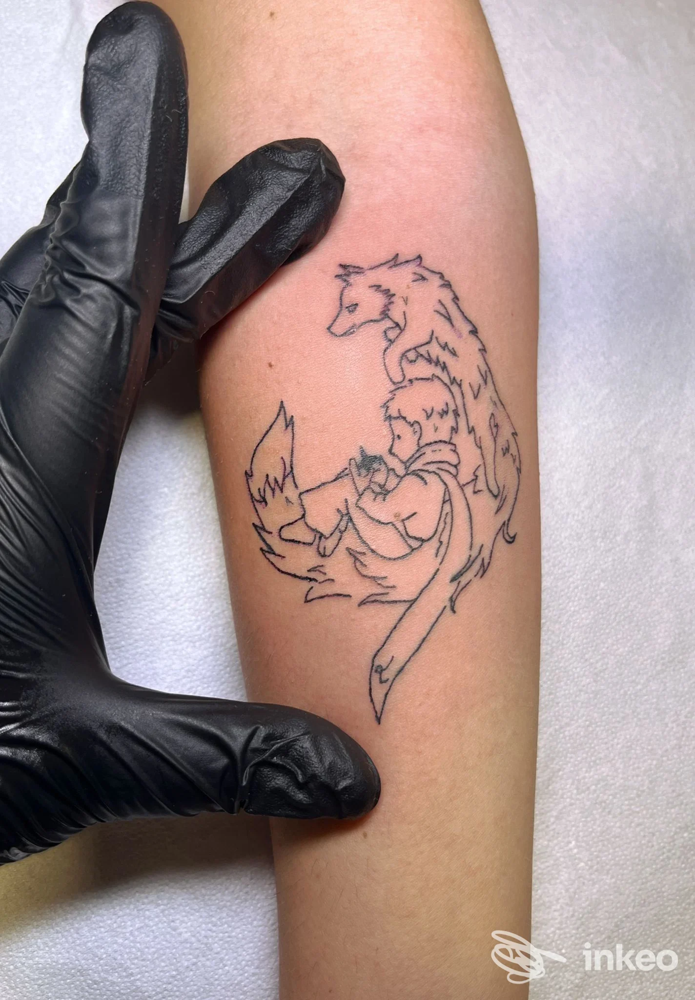 Tatuaggio a linee nere su avambraccio raffigurante una figura abbracciata da una volpe, foto dallo studio The Lovers APS a Tremestieri Etneo.