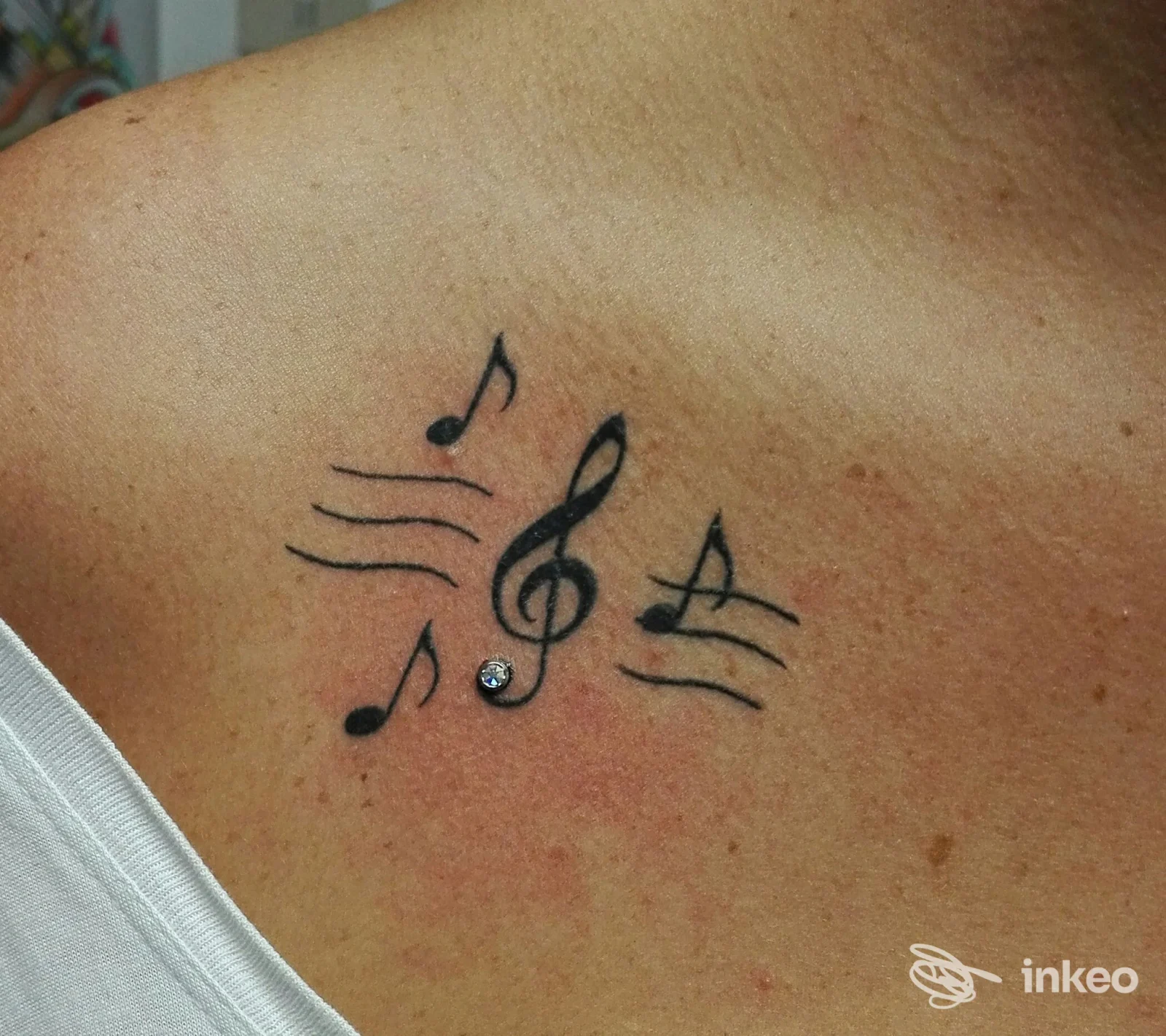 Tatuaggio musicale con chiave di violino e note sulla spalla, scatto dello studio Hd piercing -tatuaggi Family Olbia, Olbia.
