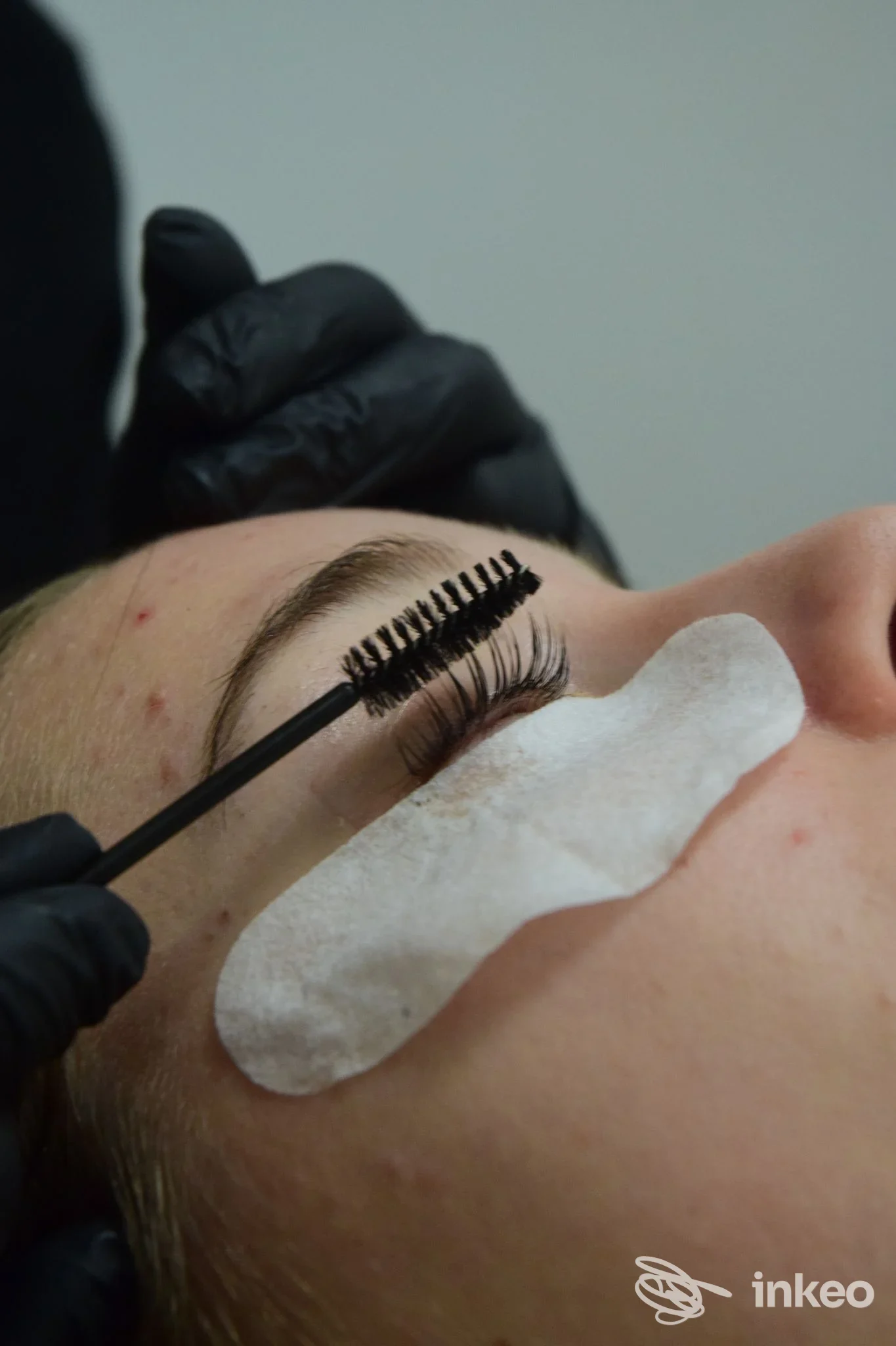 Dettaglio procedura ciglia: cliente sdraiata con patch sotto occhi mentre l'operatore pettina le ciglia allo studio Beauty Premiére® Arezzo, Arezzo.