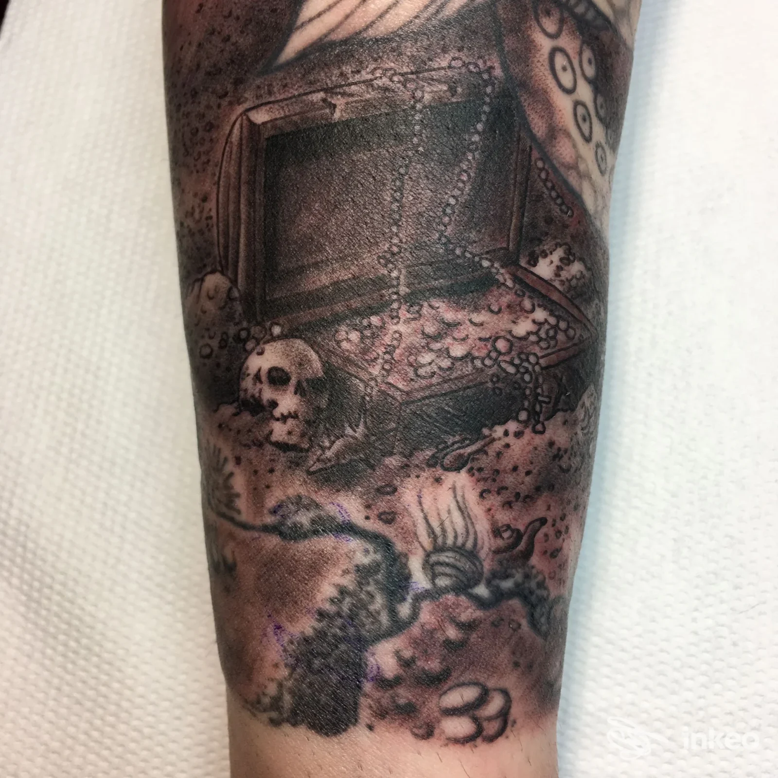 Tatuaggio su avambraccio raffigurante forziere, monete, teschio e tentacoli, opera fotografata dallo studio Dr. Frankestein Tattoo a Scandicci.