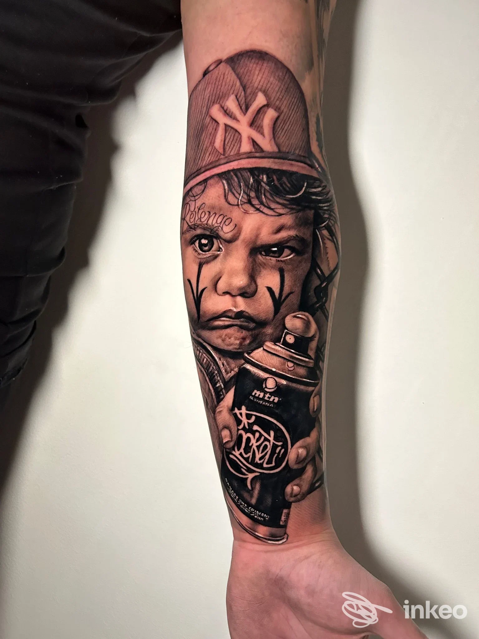 Tatuaggio realistico in bianco e nero su avambraccio raffigurante un bambino con cappellino e bomboletta, Catania City Ink, Catania.