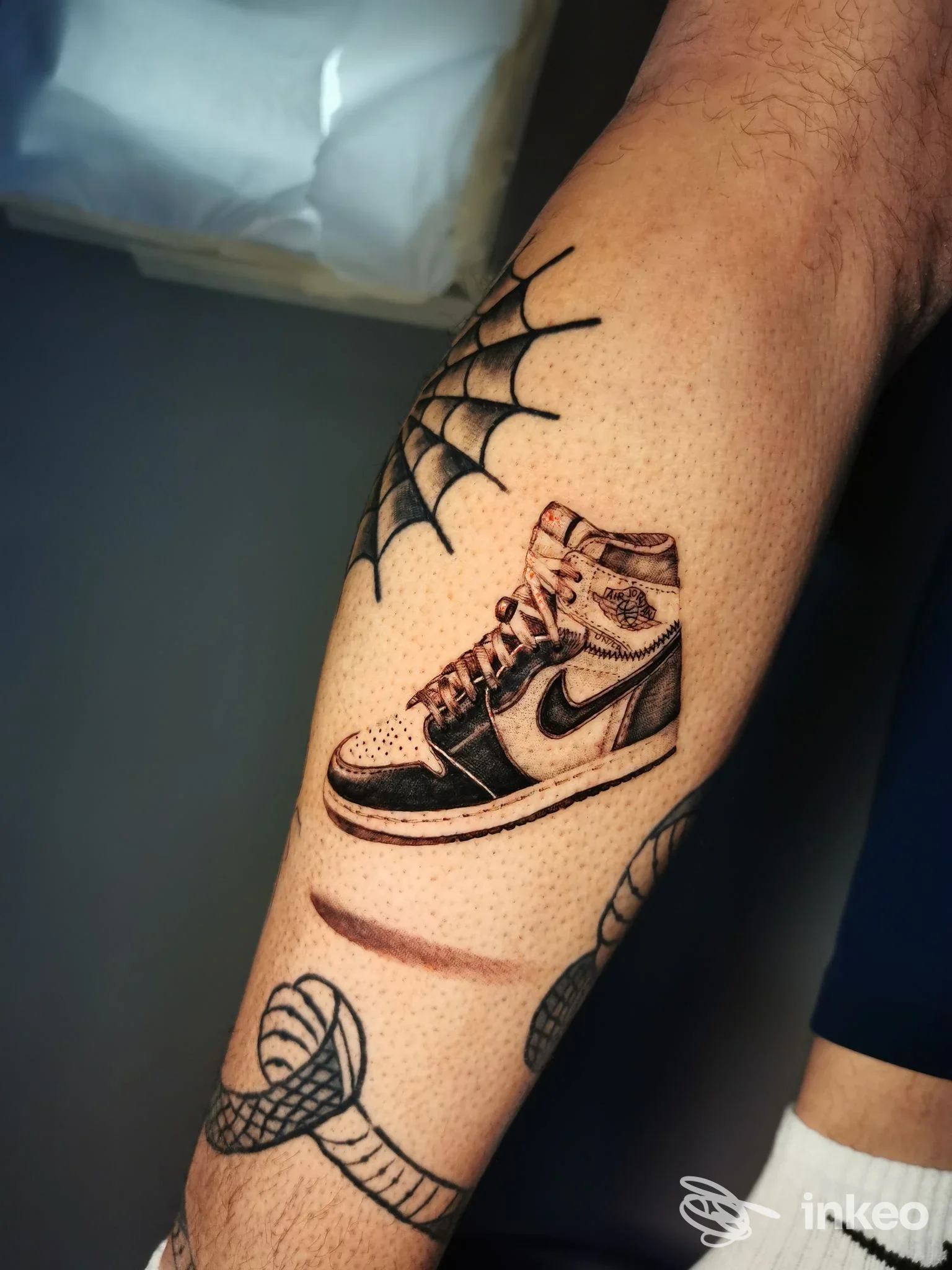 Tatuaggio di una scarpa in stile sneaker e una ragnatela sull'avambraccio, Catania City Ink, Catania.