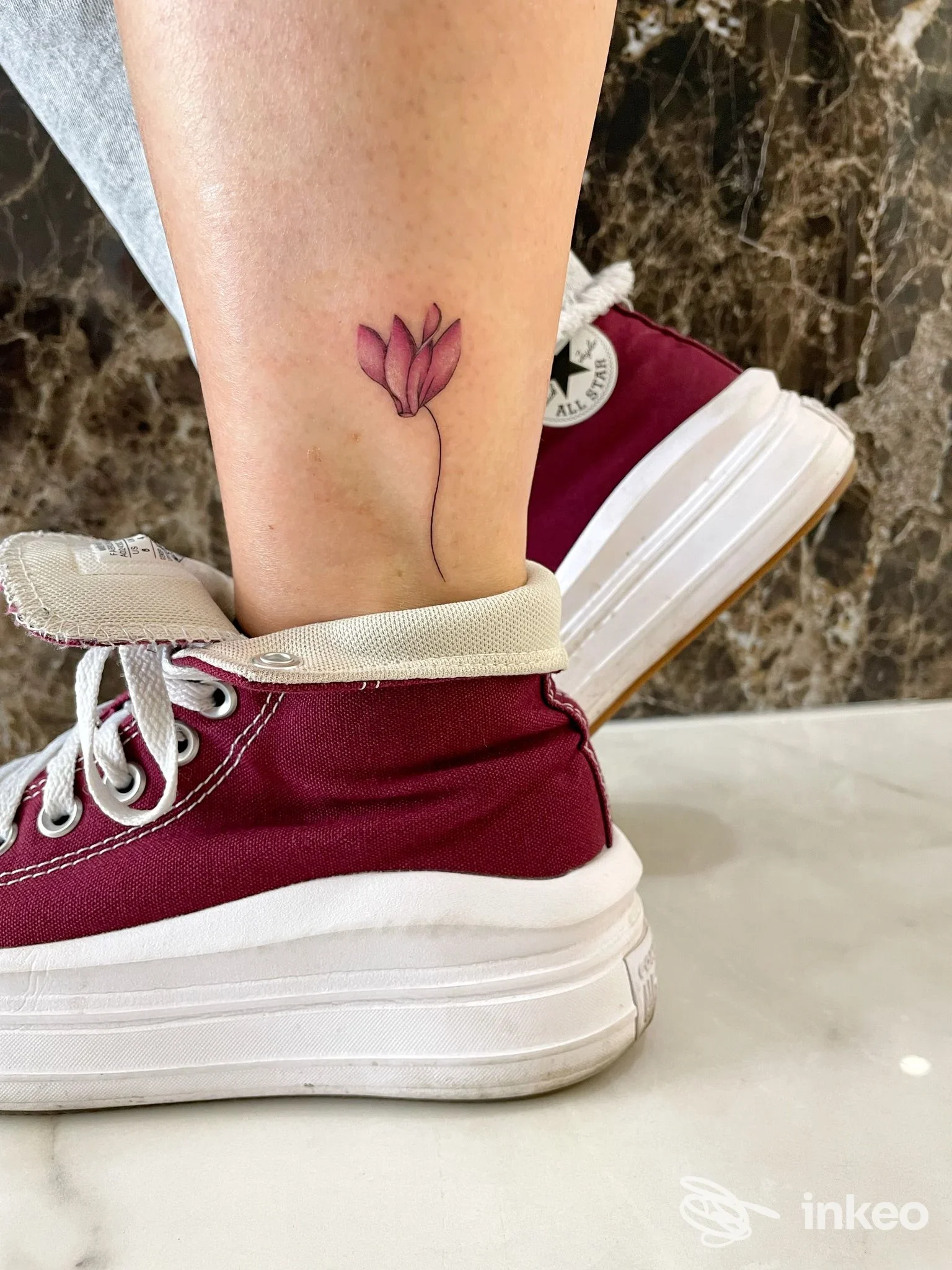 Piccolo fiore stilizzato tatuato sulla caviglia, fotografato su pelle reale. Micaela De Carli Tattoo, Olbia.