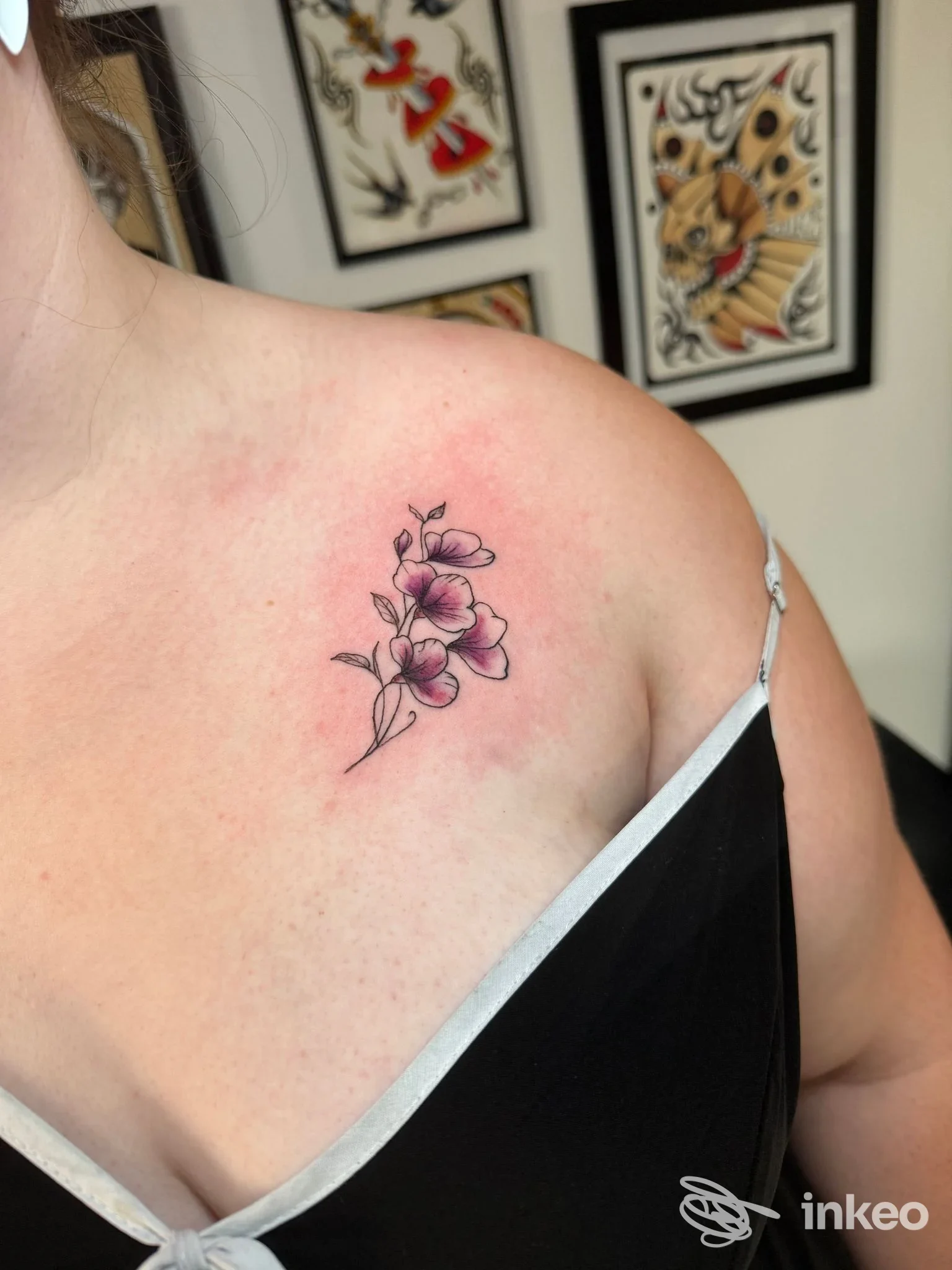 Piccolo tatuaggio floreale rosa e nero sulla clavicola sinistra, fotografato da vicino — Bettie Love Tattoo Studio, Olbia.