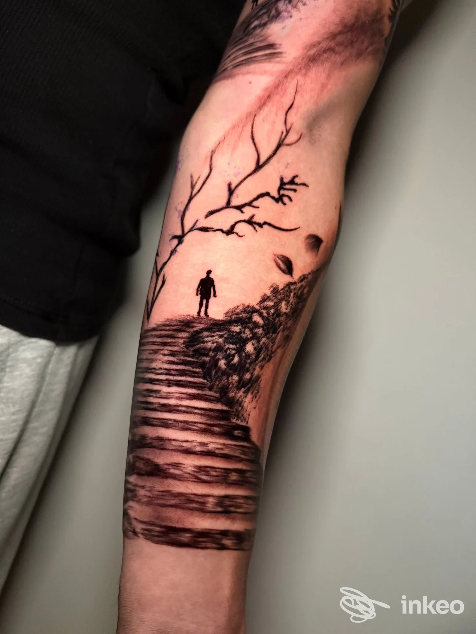 Tatuaggio a firma Bettie Love Tattoo Studio a Olbia: scalinata e silhouette su avambraccio, lavoro in nero e grigi.