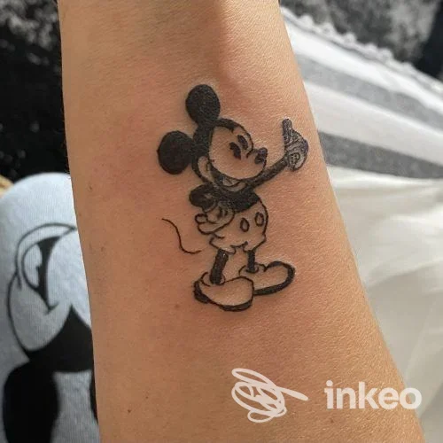 Tatuaggio in bianco e nero su avambraccio raffigurante un topo in stile cartoon. Immagine fornita dallo studio Andreea Beauty Studio, Arezzo.