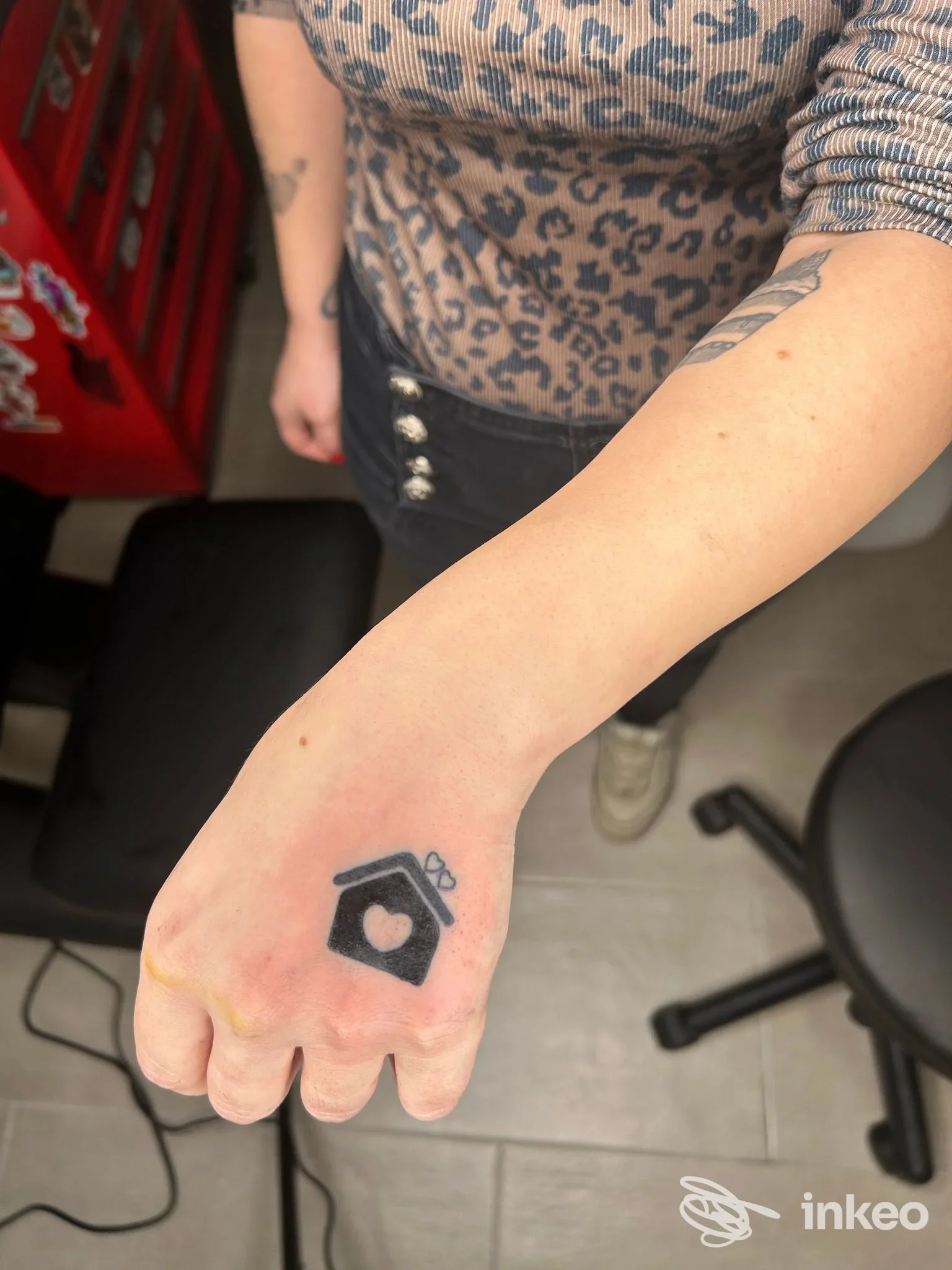 Foto del tatuaggio sul dorso della mano con una casetta nera e un cuore, realizzato da Litta tattoo lab a Portoscuso.