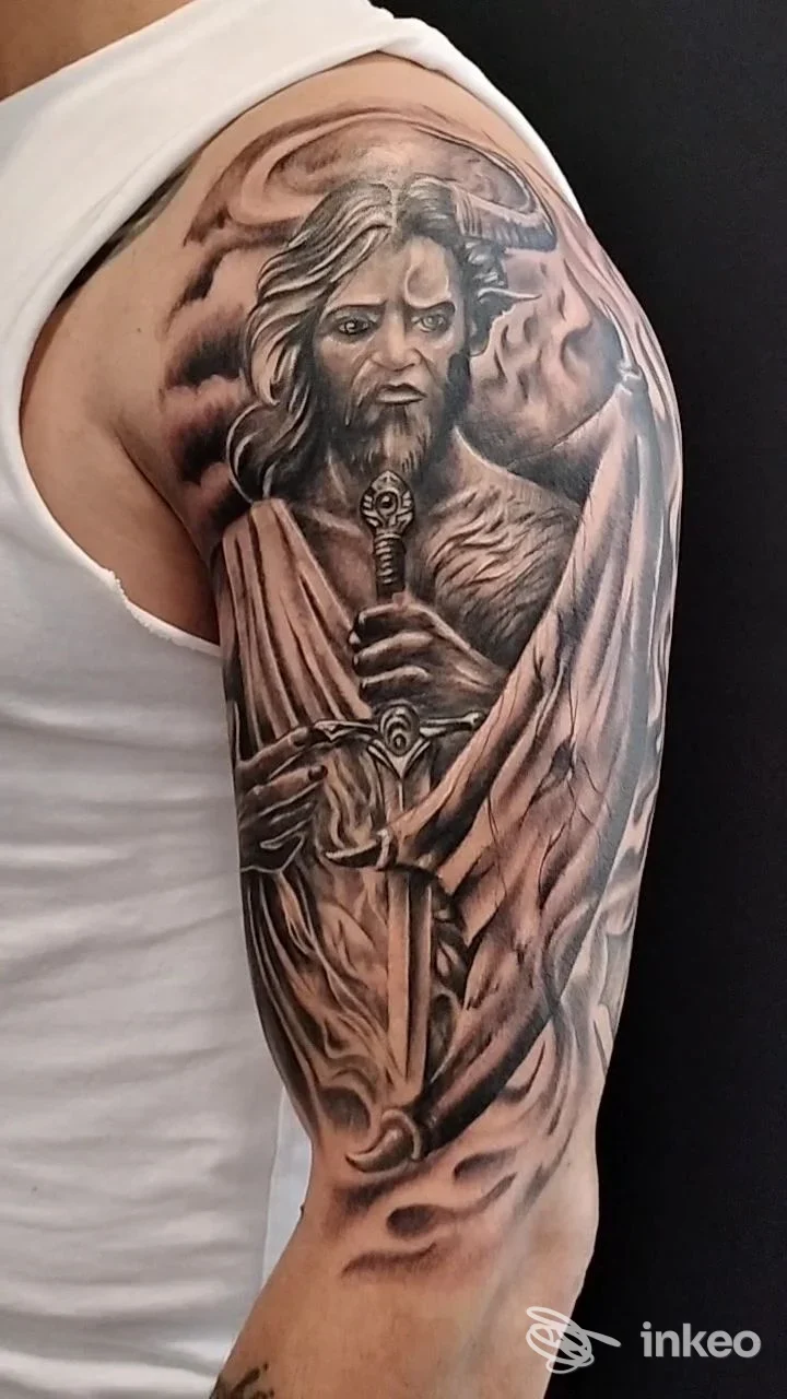Tatuaggio realistico in bianco e nero su spalla e bicipite: figura barbuta con spada. Andromac'Art Tattoo-Piercing, Agrigento.