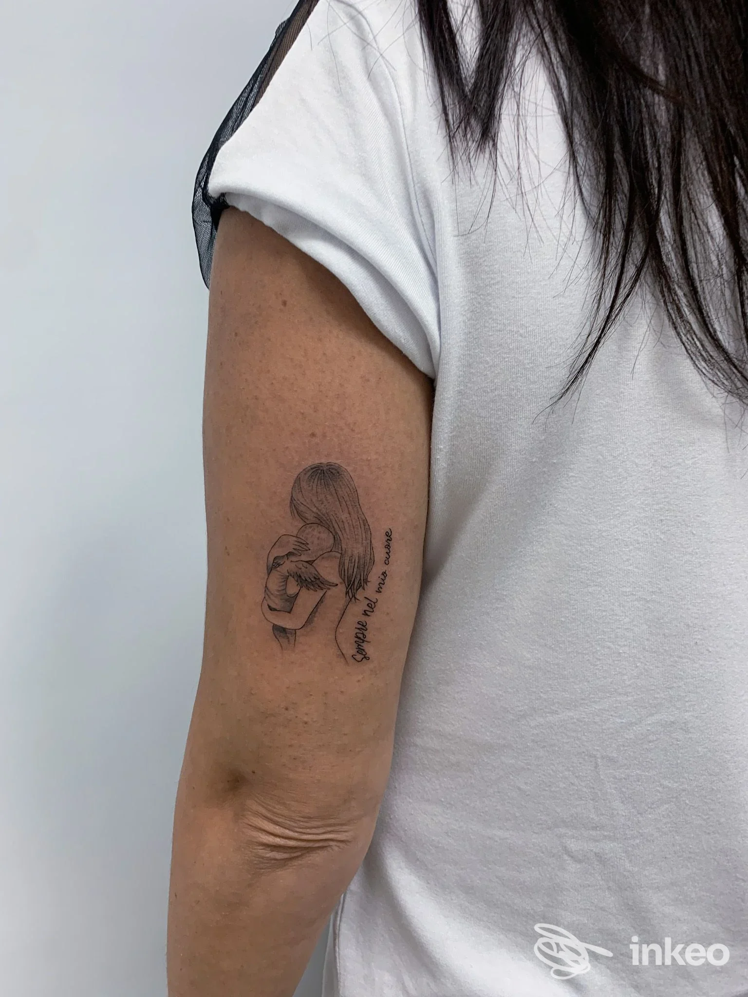 Tatuaggio linework su braccio superiore: figura che abbraccia un bambino. Ros’skin Studio, Gela.