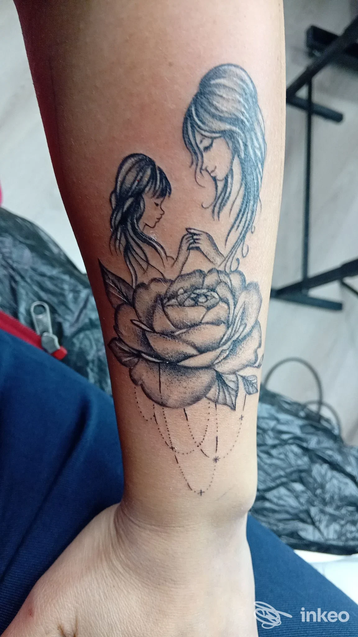 Tatuaggio in bianco e nero sull'avambraccio con una grande rosa e due figure femminili stilizzate. Studio Shining, Caltanissetta.