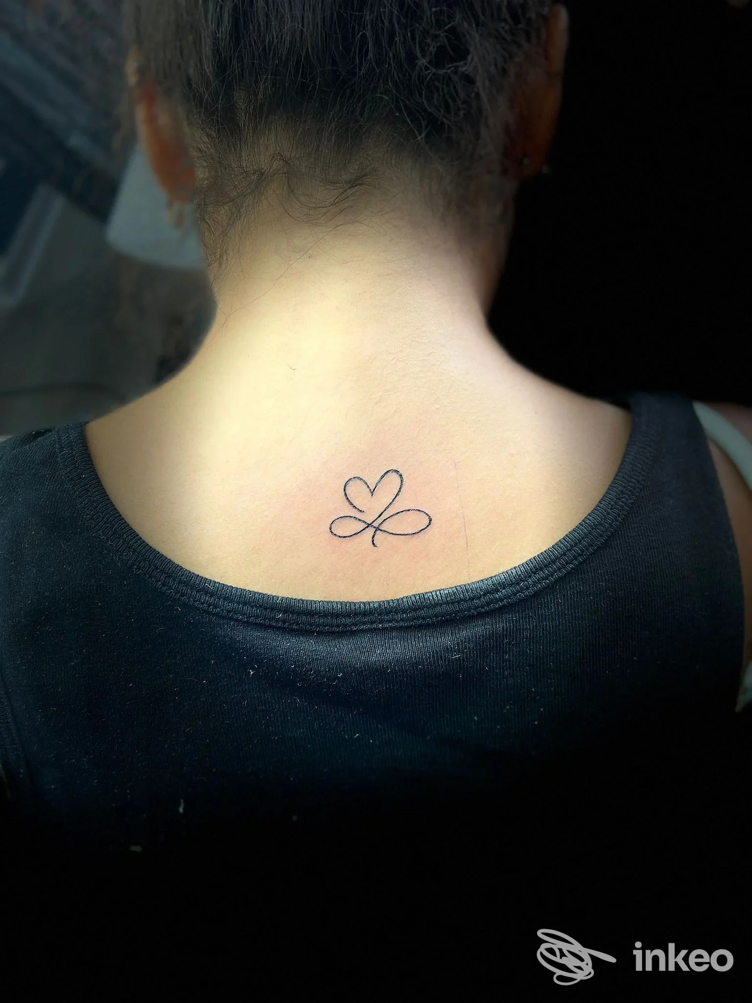 Piccolo tatuaggio minimal sulla nuca fotografato nello studio Shining a Caltanissetta, vista di schiena su pelle reale.