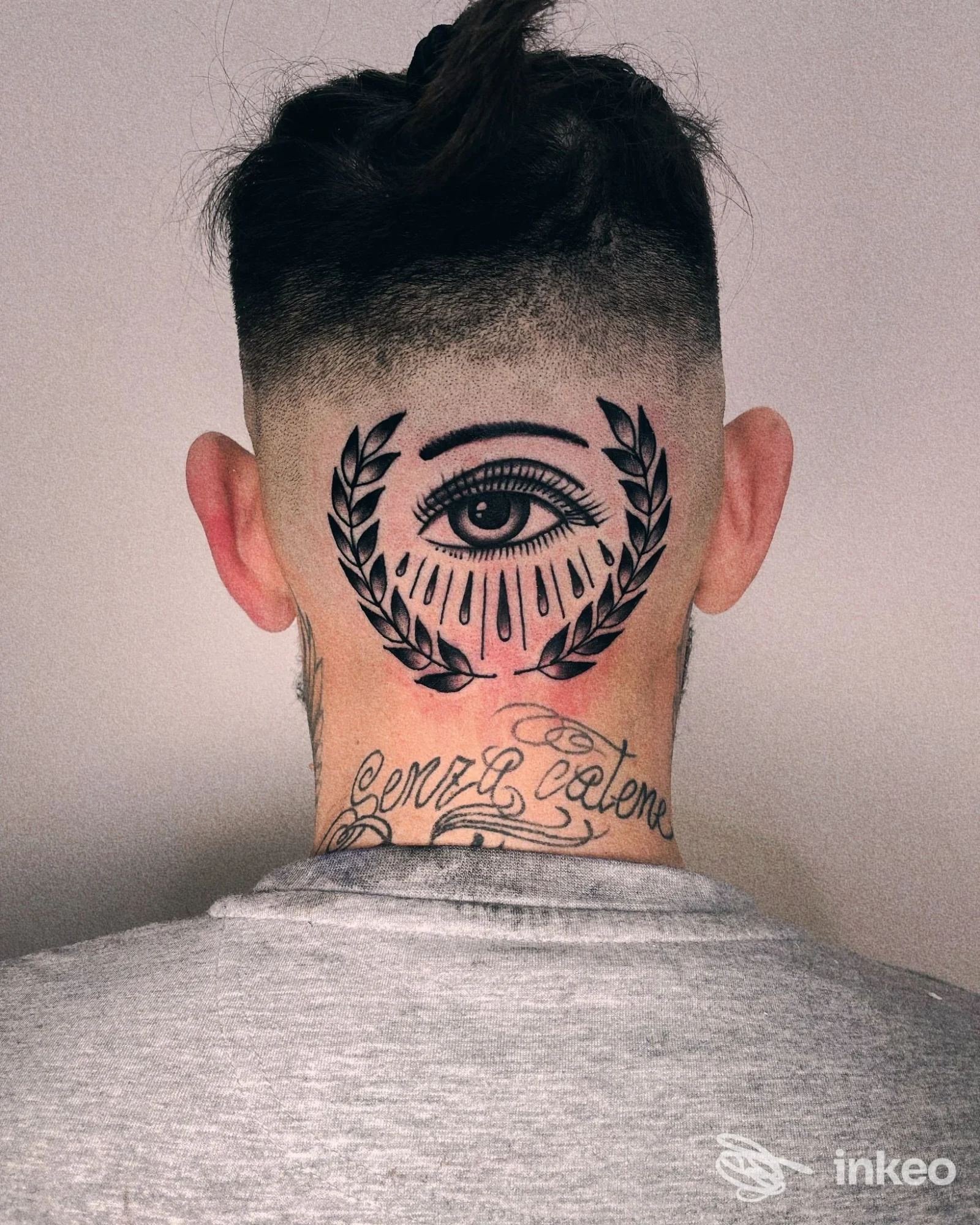 Tatuaggio a Olbia: occhio stilizzato con corona di foglie sulla nuca, Hands Across the Sea Tattoo Parlour.