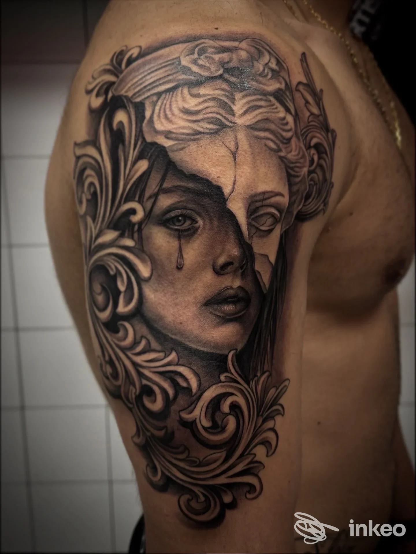 Tatuaggio realistico bianco e nero sul braccio/spalla, volti e motivi ornamentali — Mirco Ragno Tattoo, Siena.