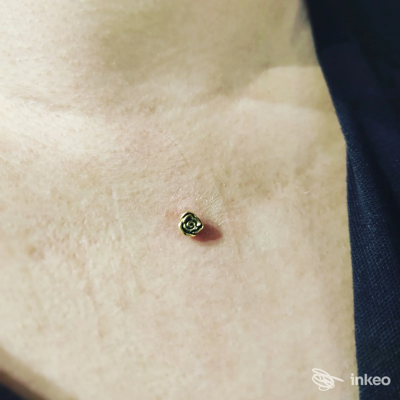 Dermal piercing floreale sul petto in primo piano, gioiello dorato. Eseguito presso Piercing & Beauty Center, Firenze.
