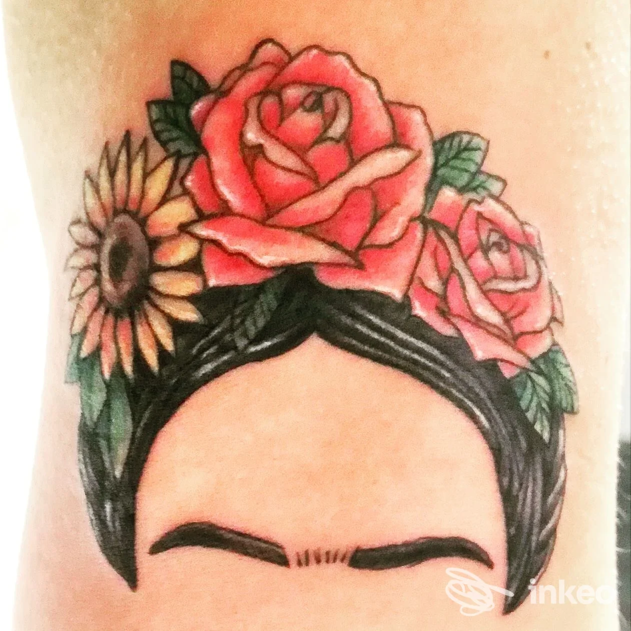 Tattoo colorato di floreali su testa/fronte, con capelli scuri; la pelle mostra chiaramente l’opera come tatuaggio corporeo. Studio Underskin Tattoo.