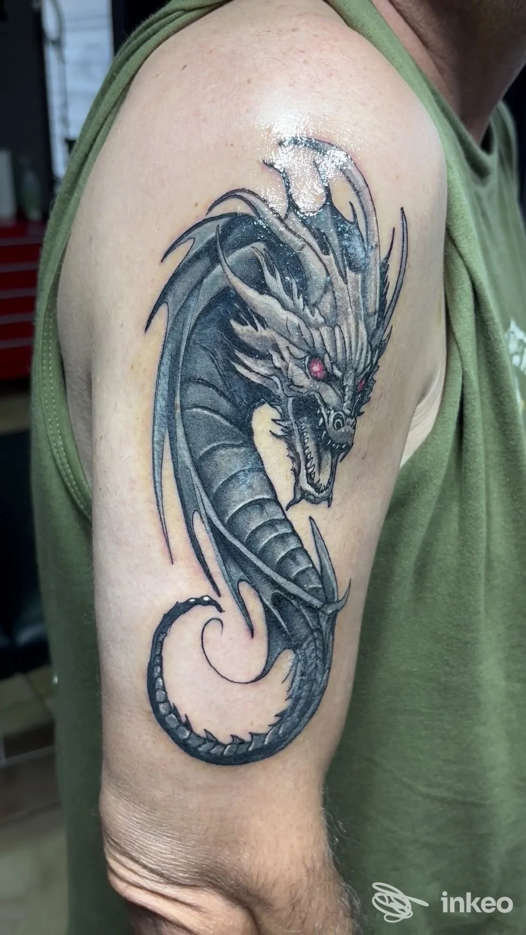 Tatuaggio di drago in bianco e nero con dettaglio occhio rosso sul braccio superiore. ZIU TATTOO ART, Domusnovas.