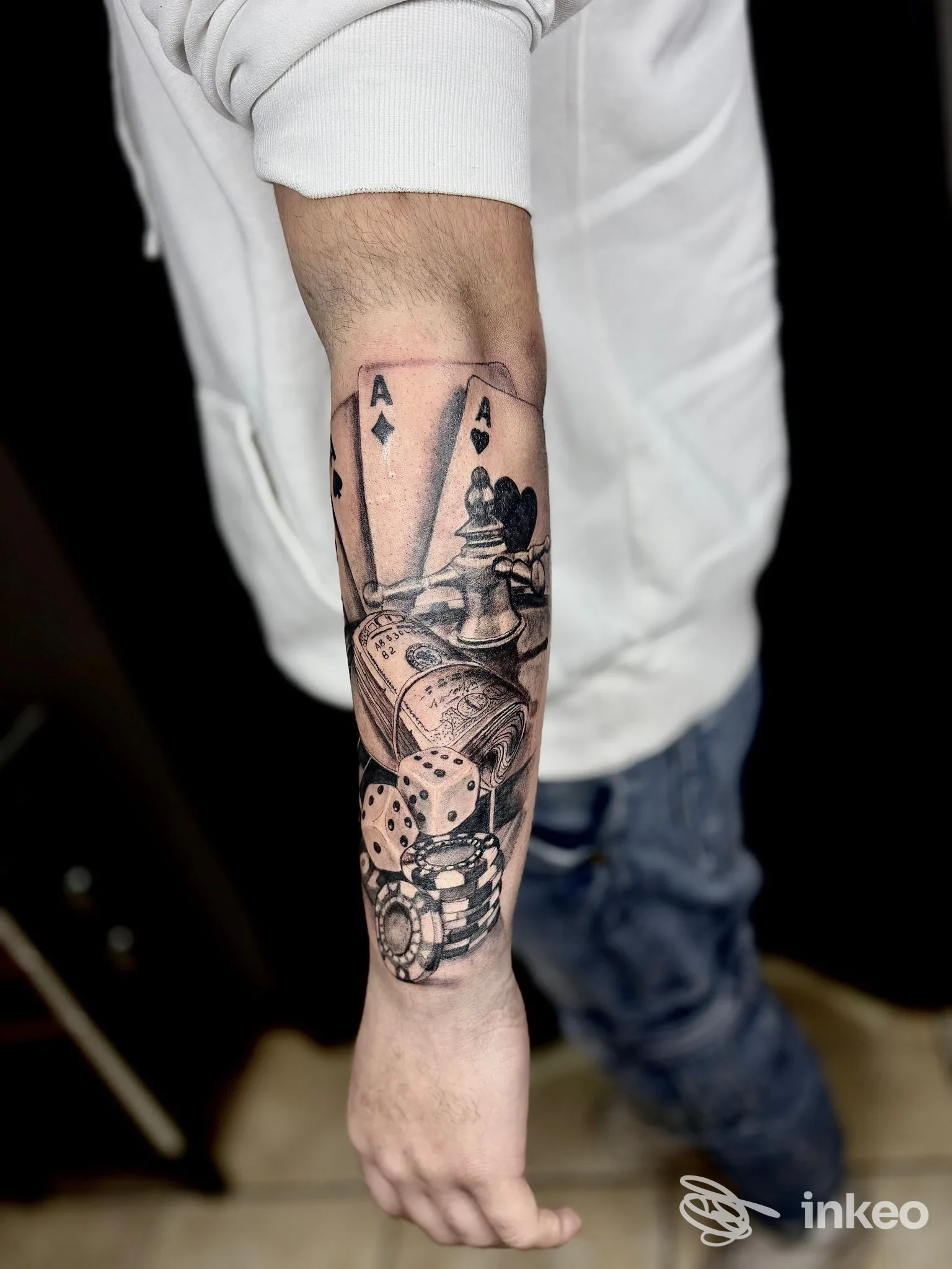 Avambraccio tatuato con carte, dadi e fiches in stile nero/grigio, foto per ZIU TATTOO ART a Domusnovas.