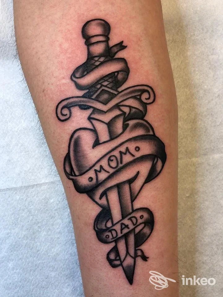 Tatuaggio tradizionale su avambraccio: pugnale con nastro recante "MOM" e "DAD", foto inviata da Mystyle, Villabassa.