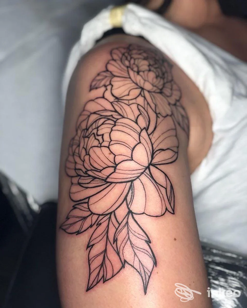 Tatuaggio floreale a linee nere sul braccio e spalla realizzato da Mystyle a Villabassa, inquadratura ravvicinata.
