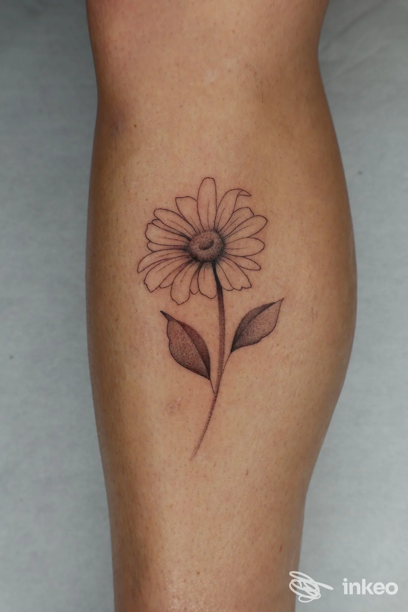 Tattoo a fiore sul braccio: disegno floreale con stelo e due foglie, realizzato direttamente sulla pelle.