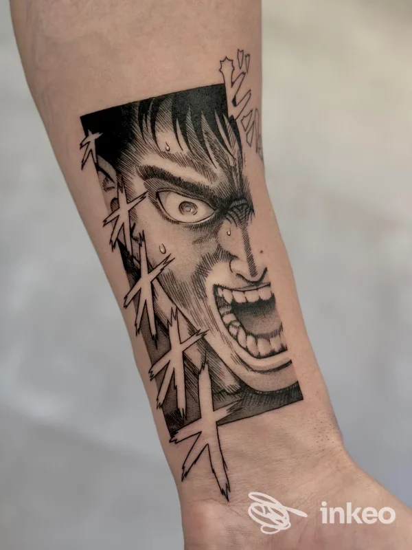 Primo piano di un tatuaggio stile manga con un volto urlante e caratteri giapponesi sull'avambraccio. No Name Tattoo Gallery, Massa.