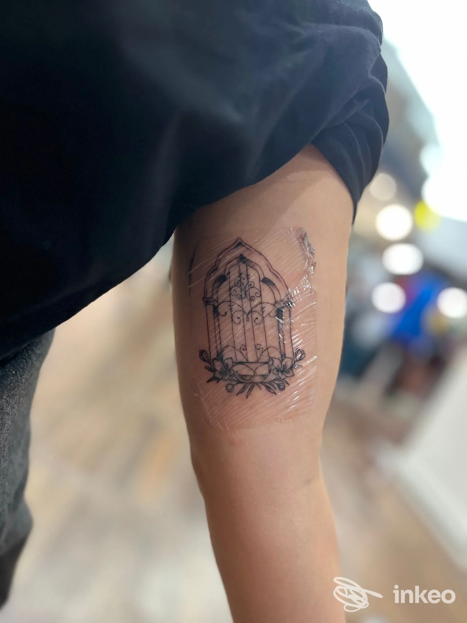 Tatuaggio a linee sottili raffigurante una finestra con fiori, interno braccio; UnderSkin, Venezia.