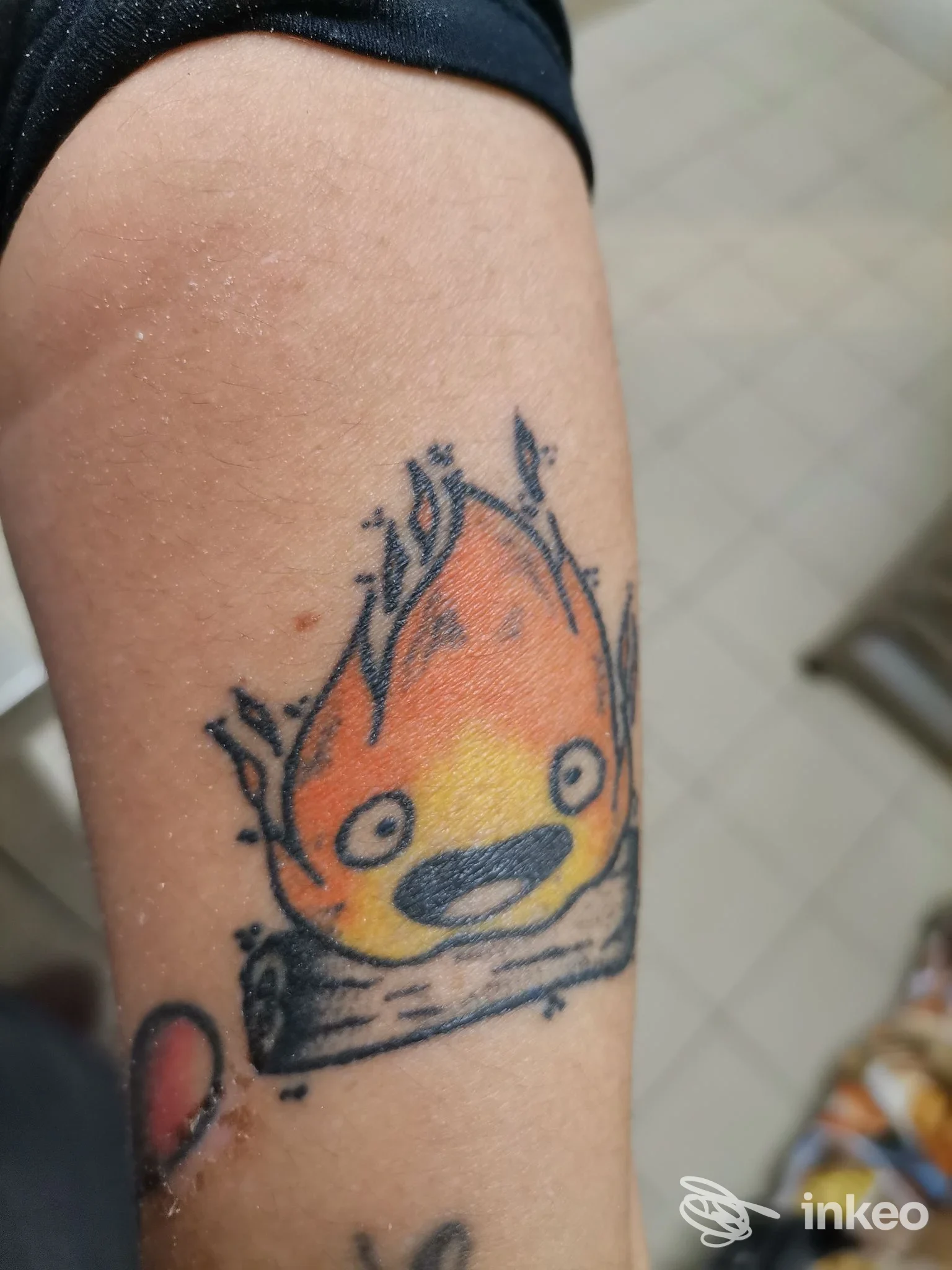 Tatuaggio cartoon di una fiamma su tronchetto sull'avambraccio, Tattooine Studio, Orbetello.