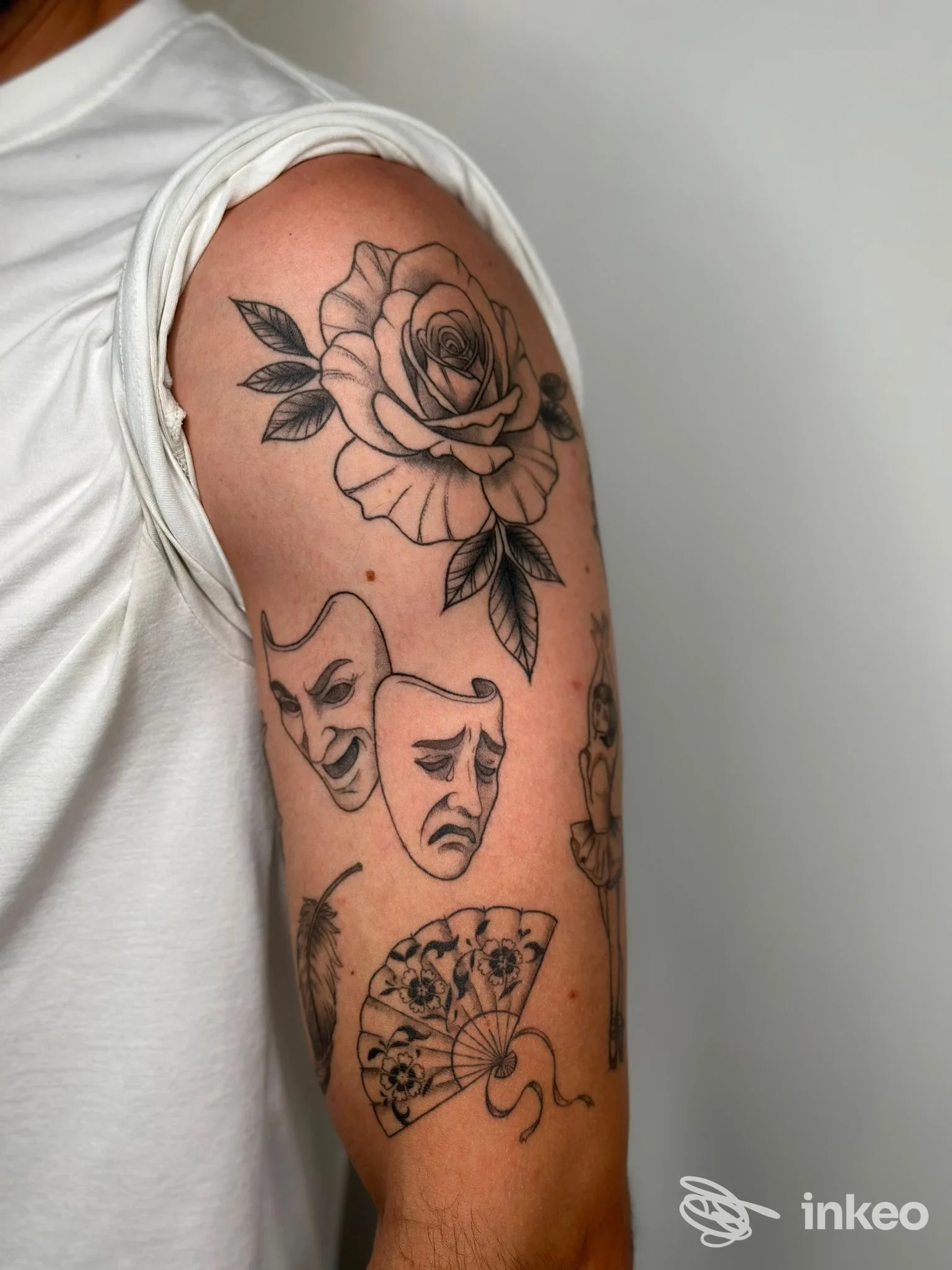 Tatuaggi a linee nere sul braccio superiore: rosa e maschere teatrali, foto fornita da nerocorpus a Quinto di Treviso.
