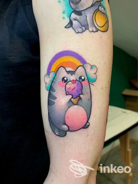 Tattoo colorato su avambraccio raffigurante un animale simpatico che tiene un ghiacciolo; angolo del gomito visibile, stile cartoon, colori vivaci, senza testo né watermark.