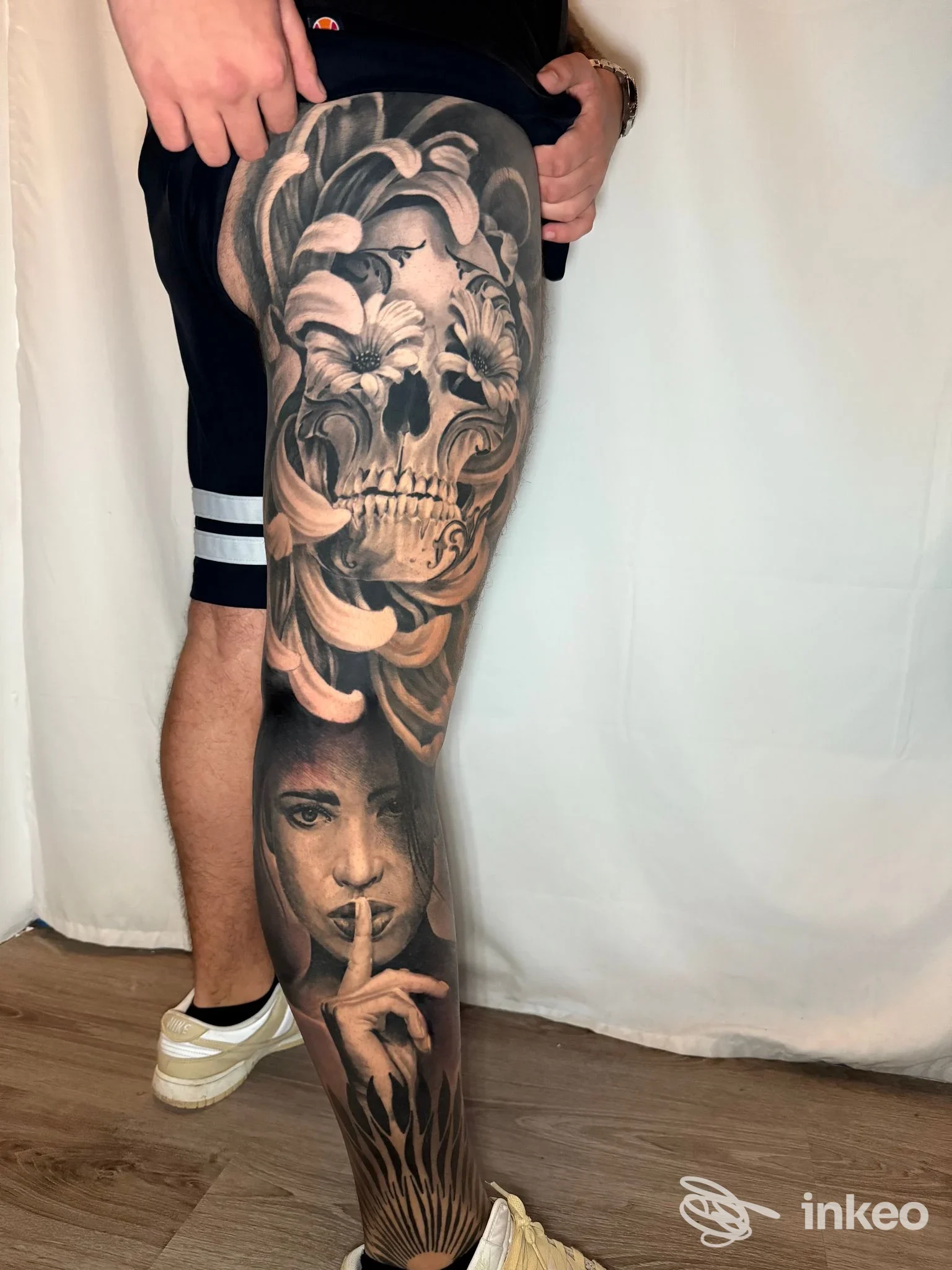 Tatuaggio realistico su coscia e polpaccio realizzato da Eternografia, Lucca: teschio ornamentale e volto con dito sulle labbra.