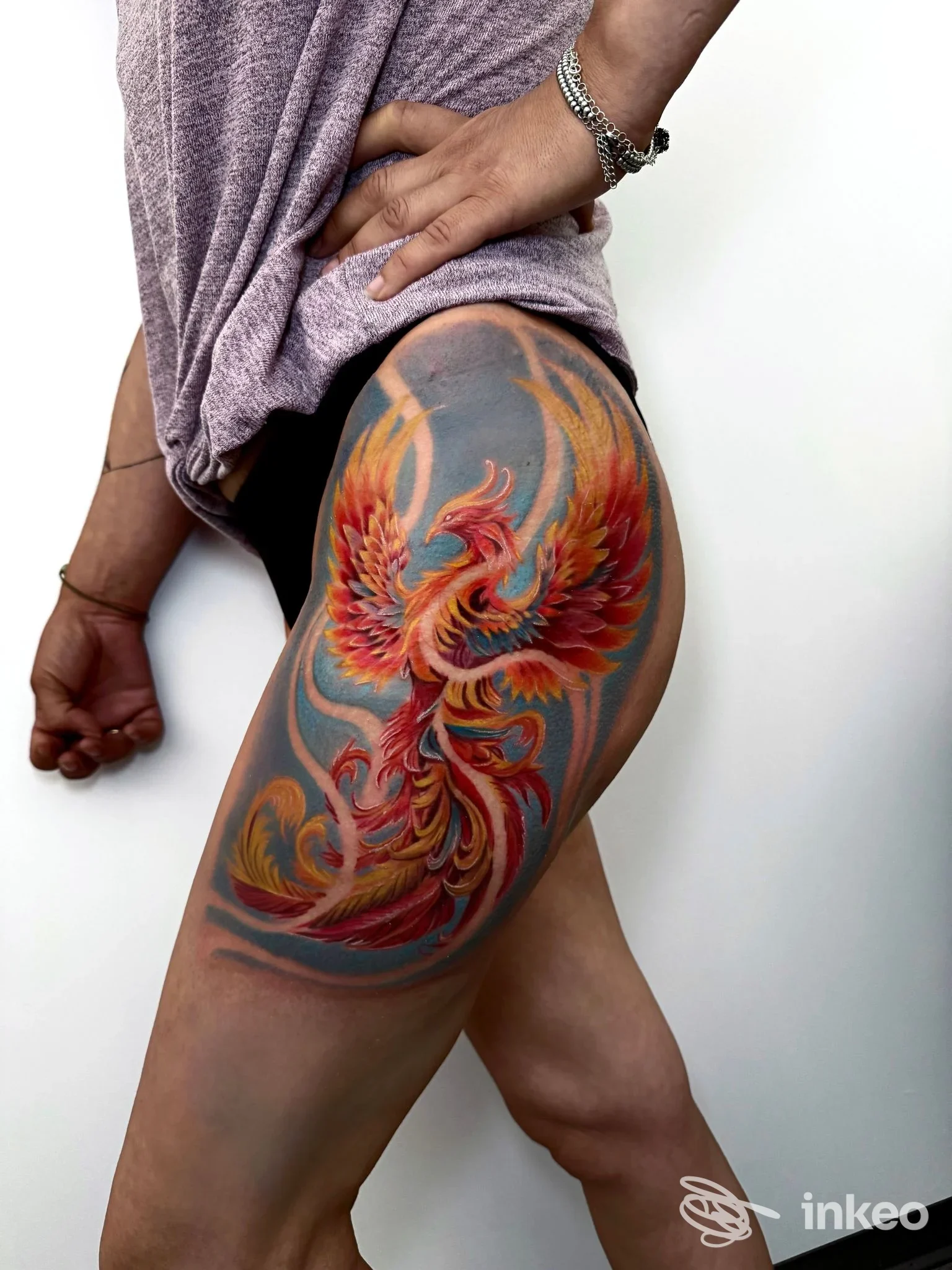Tatuaggio colorato a tutta coscia raffigurante una composizione di piume e fiamme, foto fornita da Golden Bullet tattoo & piercing studio a Carmignano di Brenta.
