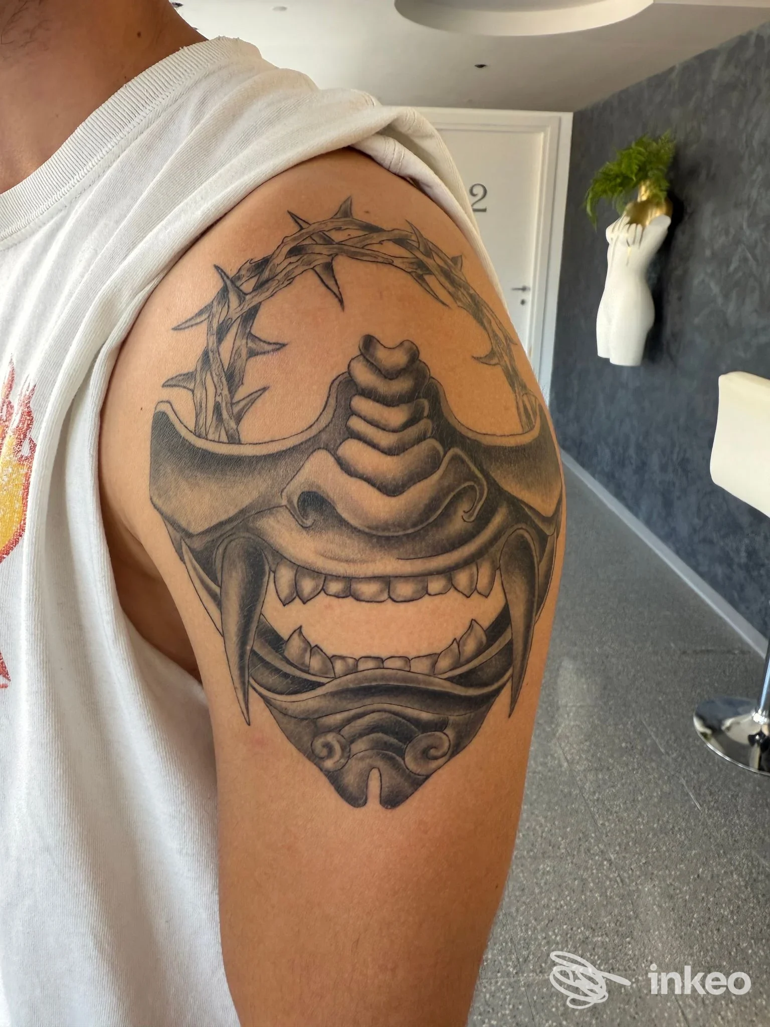 Tatuaggio blackwork su spalla con maschera e corona di spine, Golden Bullet tattoo & piercing studio, Carmignano di Brenta.