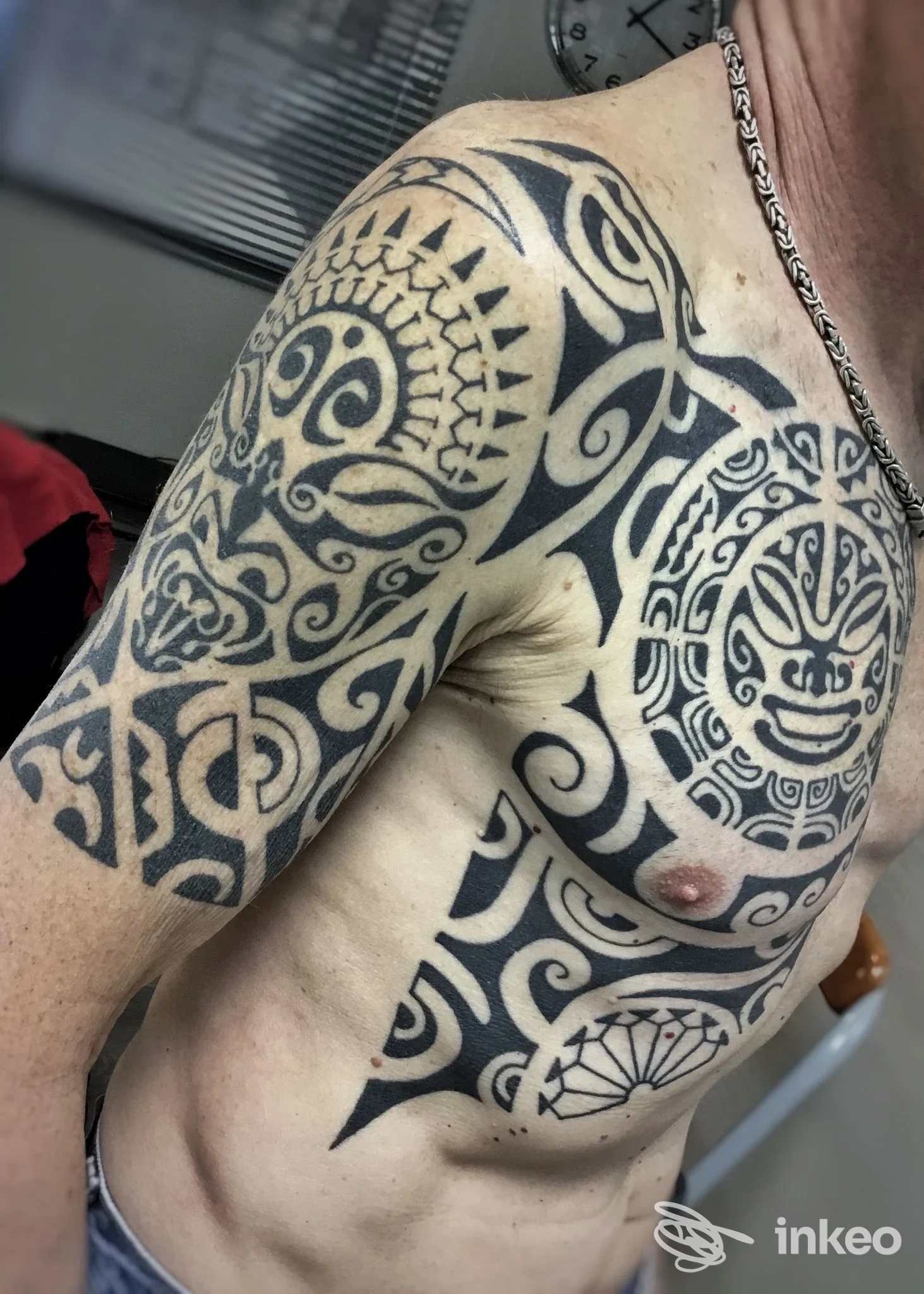 Ampio tatuaggio tribale su spalla, braccio e petto realizzato da guido tattoo a Cascina, primo piano del torso.