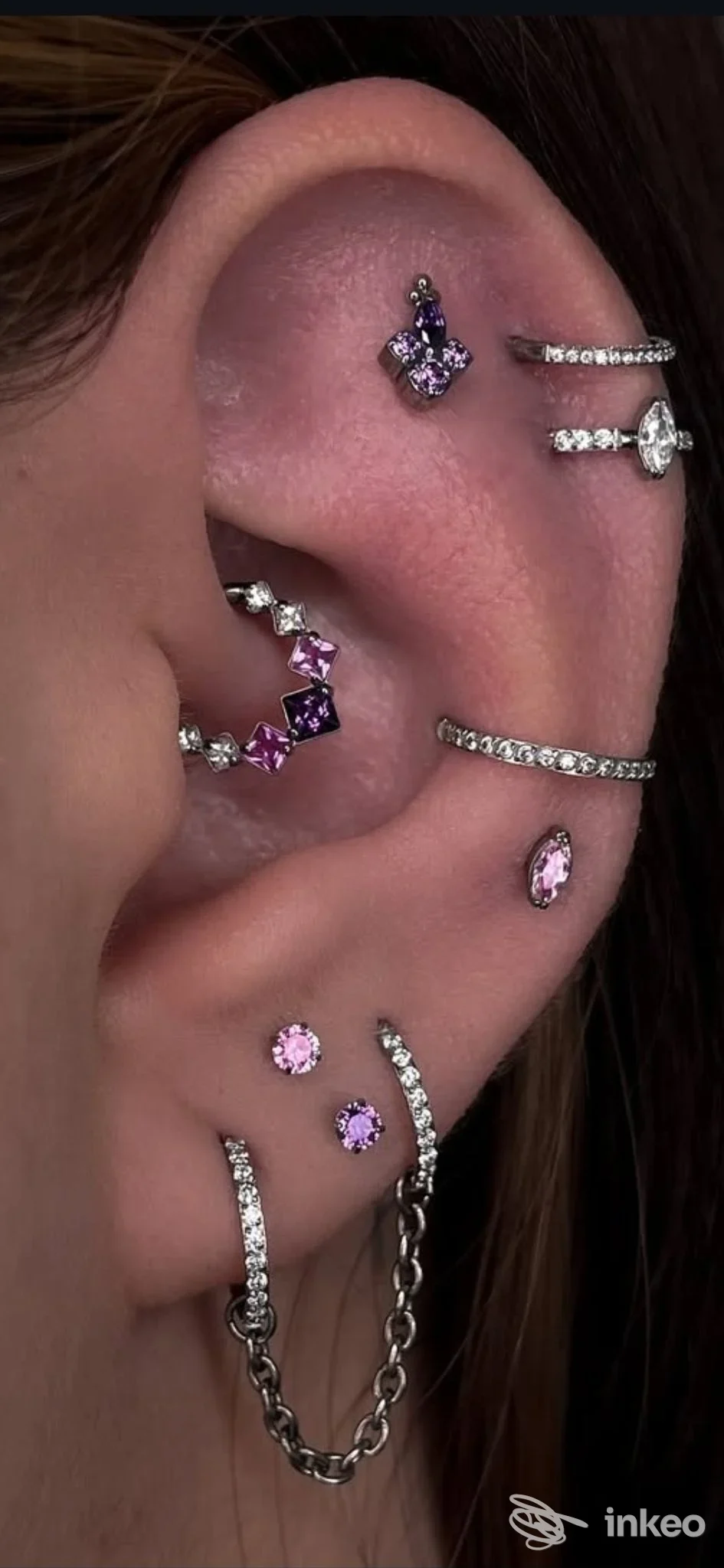 Orecchio con multipli piercing gioiello rosa e argentati, scatto vicino — Giada Make Up Artist, Livorno.