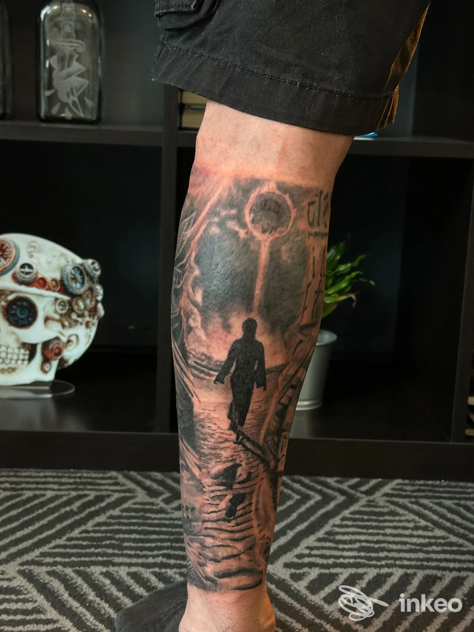 Tatuaggio black & grey su polpaccio: scena con figura in silhouette, opera presentata da Black Realism Tattoo ad Altivole.