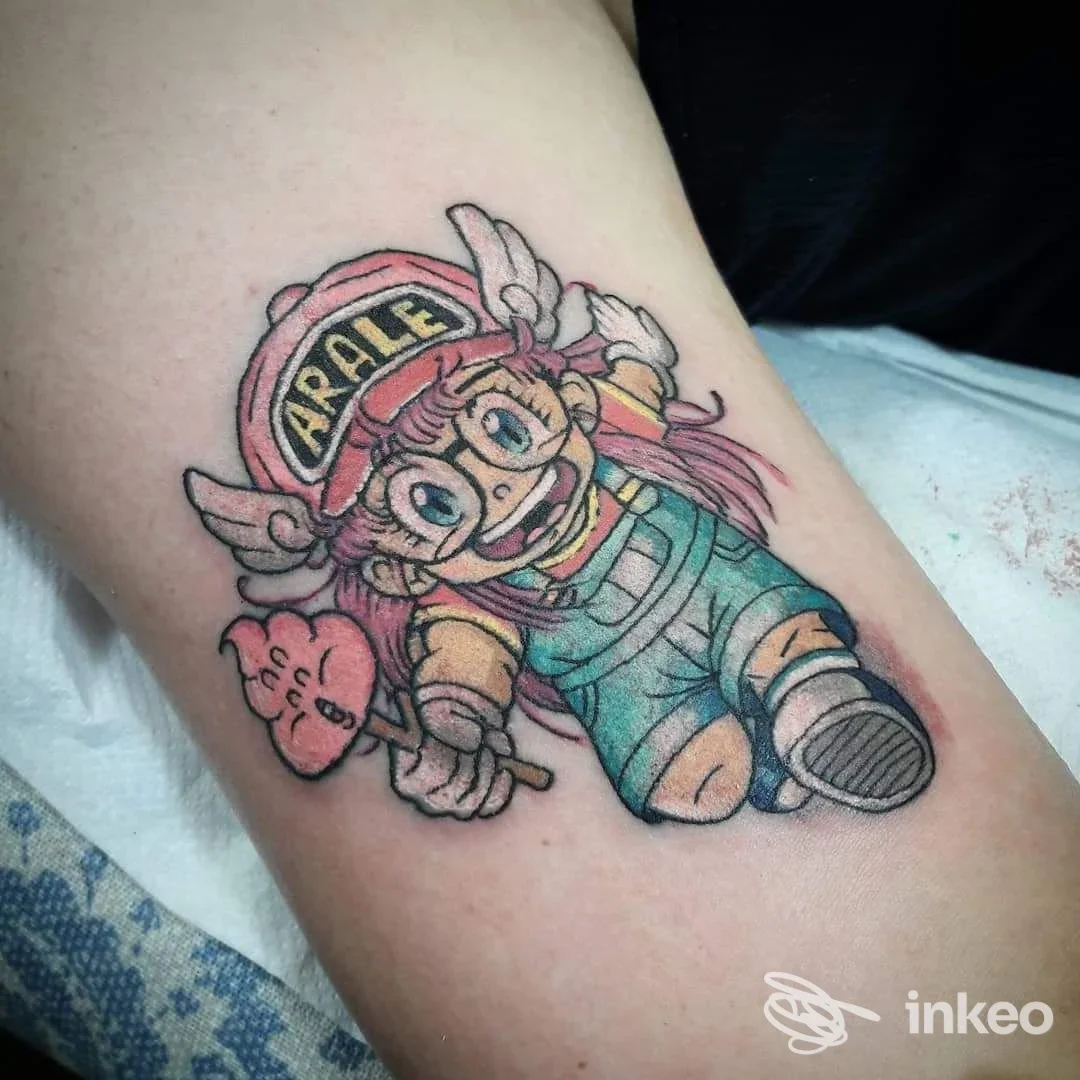 Tatuaggio colorato del personaggio Arale su pelle, eseguito da VOODOO TATTOO CLUB PADOVA a Padova, linee nitide e colori vivaci.