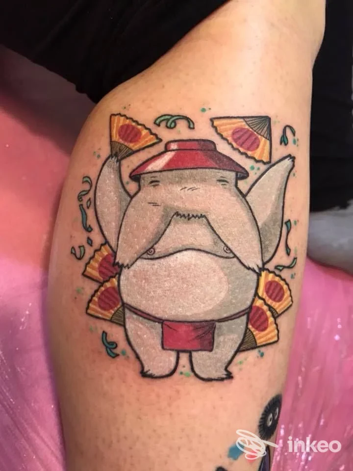 Tatuaggio colorato su coscia raffigurante un elefante-cartoon con ventagli, realizzato da The Iron Family - Tattoo & Piercing Factory, Viareggio.