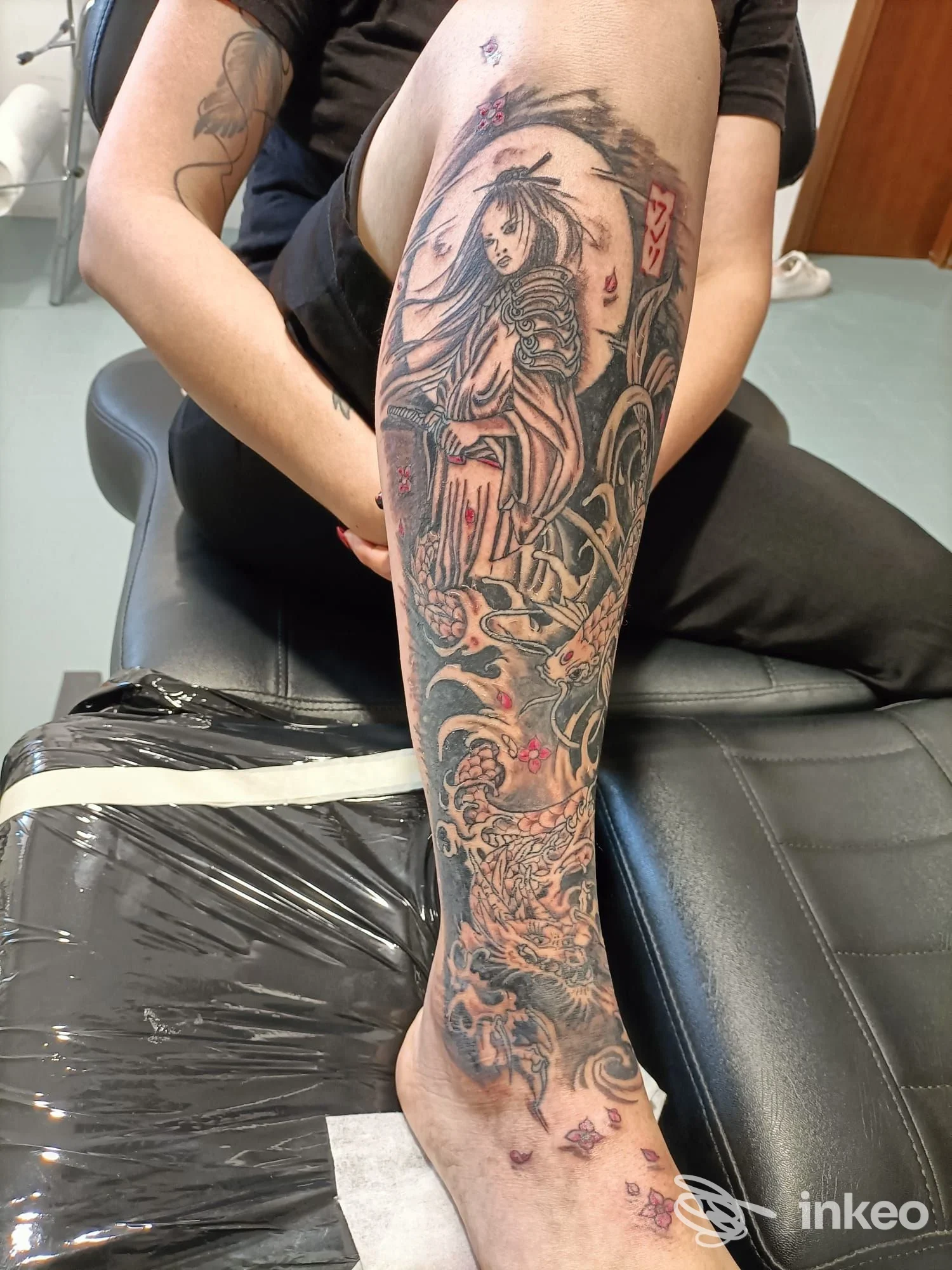 Ampio tatuaggio sul polpaccio e piede eseguito presso Rose Line Fashion, Treviso: figurativo in nero con dettagli rossi su pelle reale.