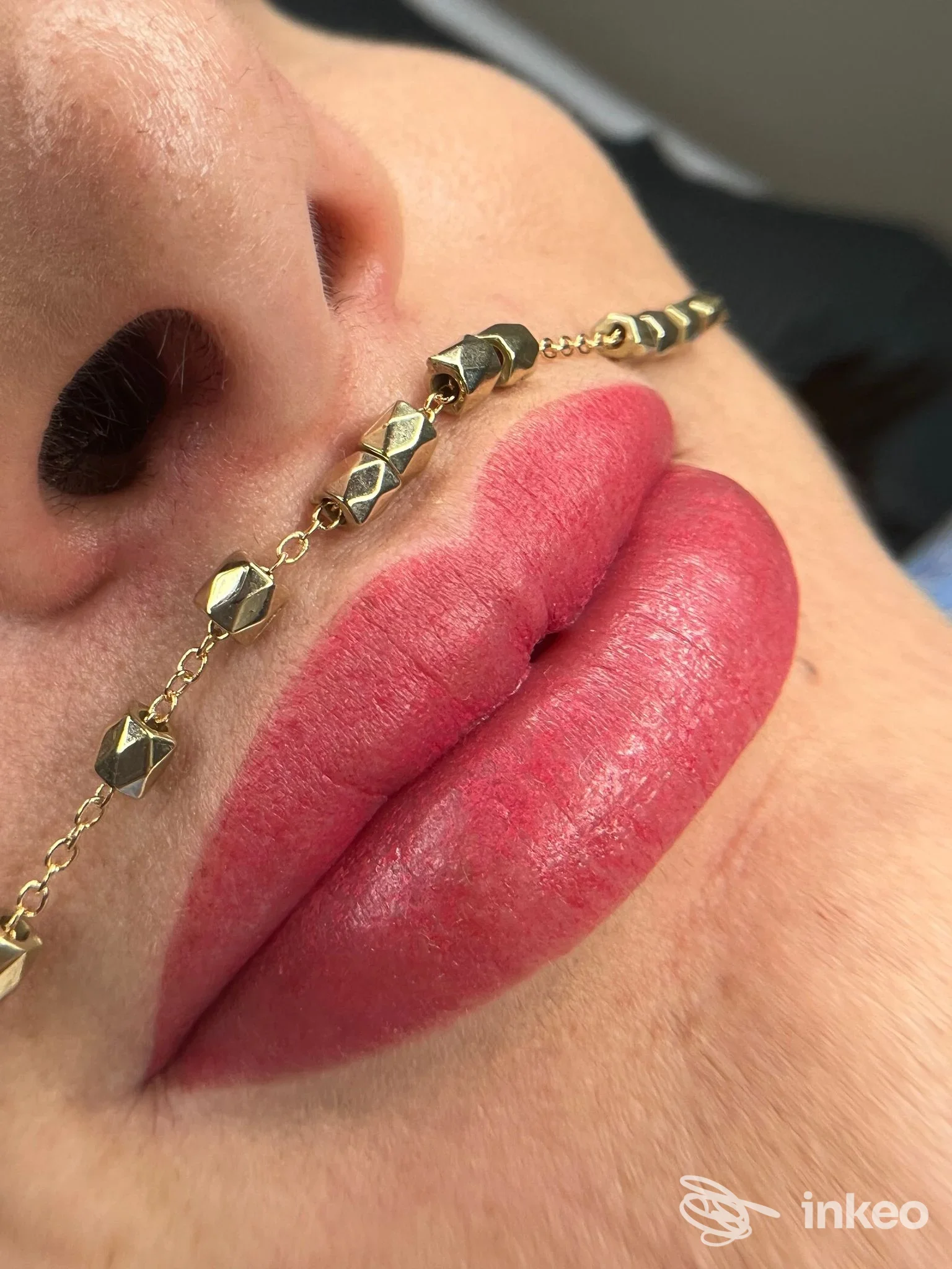 Primo piano di labbra con trucco permanente eseguito da Estetica Style 88, Livorno; visibile anche la base del naso e una catena decorativa.