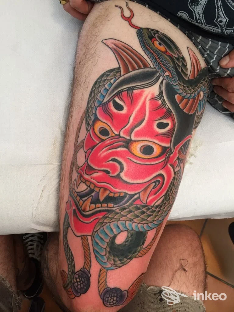 Tatuaggio su coscia con maschera Hannya rossa e serpente, eseguito da Tattoo River a Vicenza, fotografia del lavoro sul corpo.