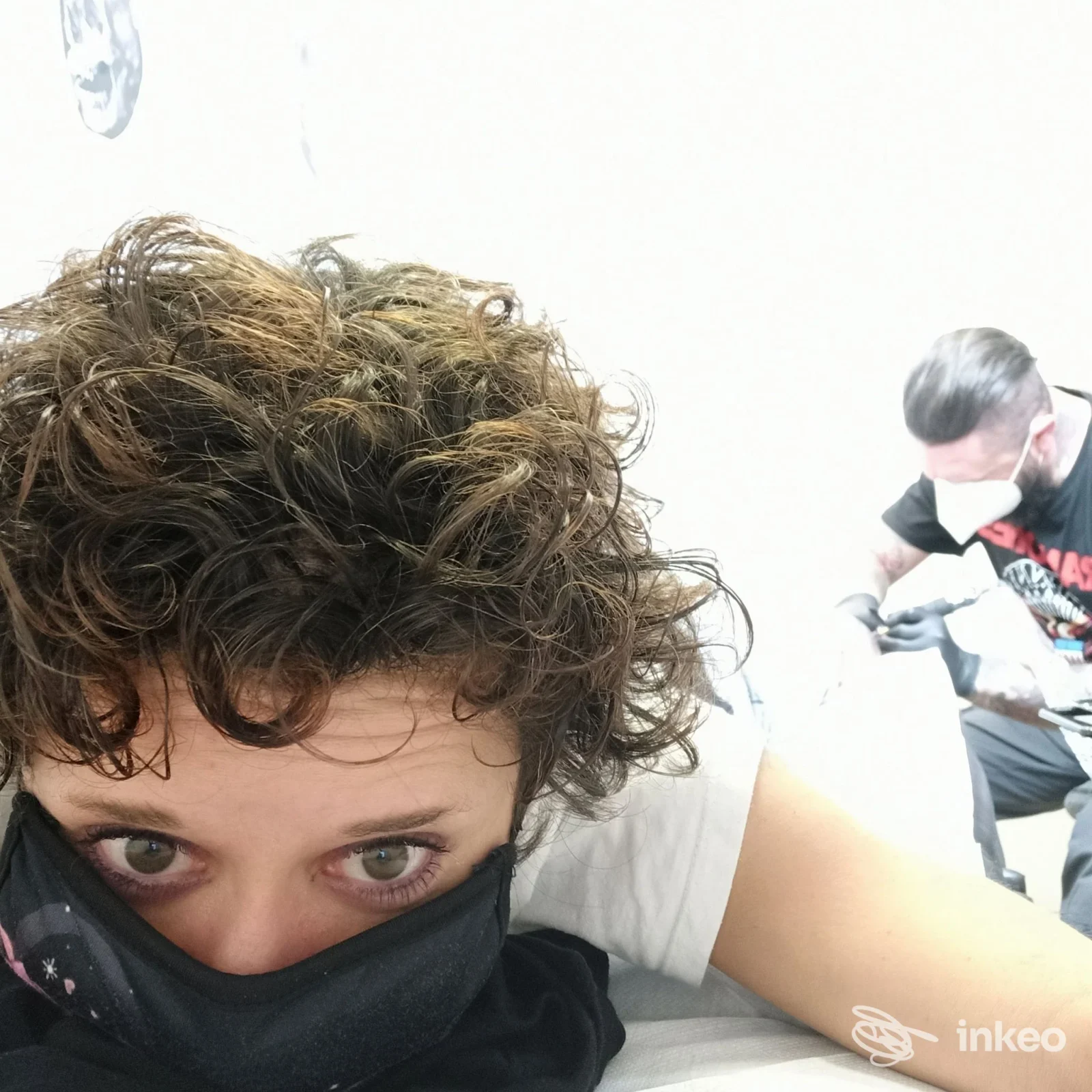 Cliente sdraiata mentre un tatuatore lavora sull'avambraccio nello studio Living Colors di Arzignano.