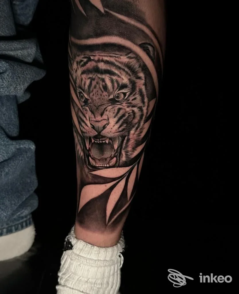 Tattoo realistico di tigre sull’avambraccio sinistro, tonalità nere e grigi, in primo piano con sfondo scuro.