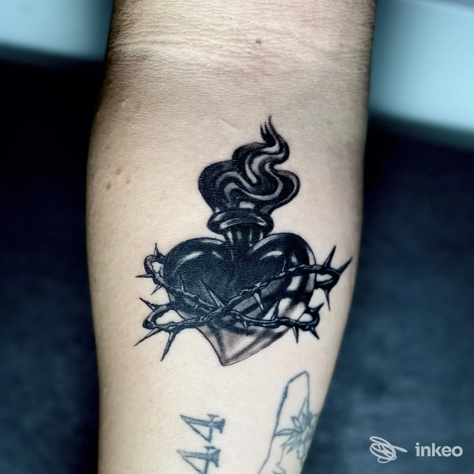 Tatuaggio sul avambraccio di un cuore fiammeggiante con corona di spine, Negozio di tatuaggi, Pagliare del Tronto