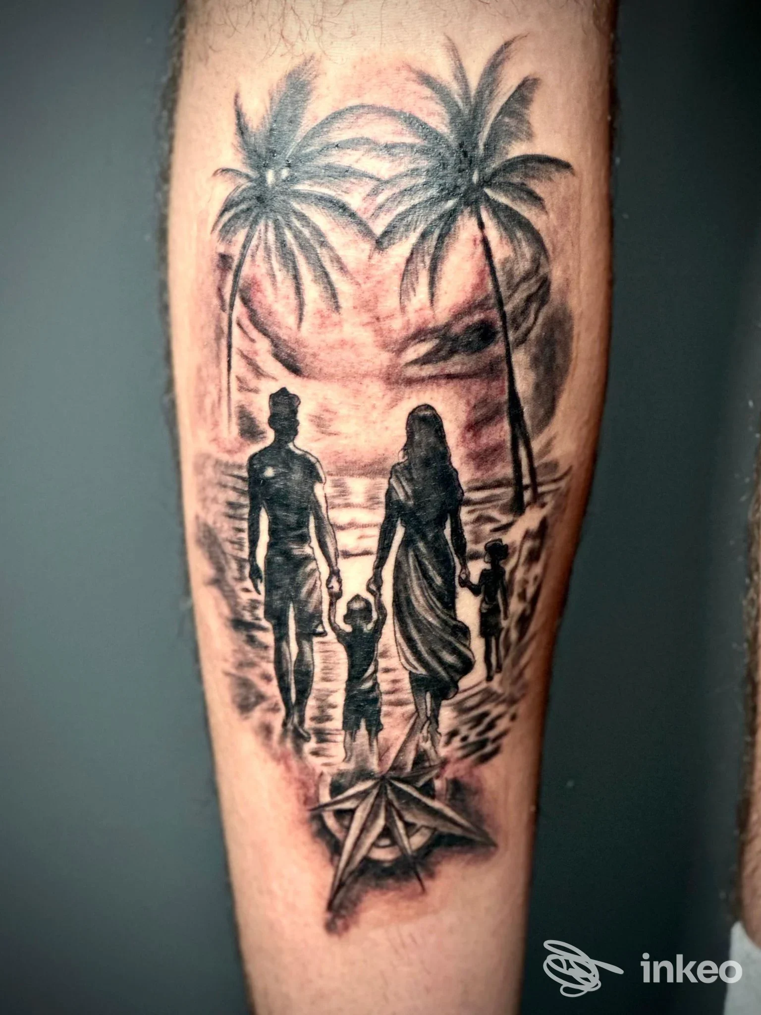 Tatuaggio realistico sul polpaccio che mostra una famiglia in controluce sulla spiaggia con palme e una bussola, realizzato da Negozio di tatuaggi a Pagliare del Tronto.