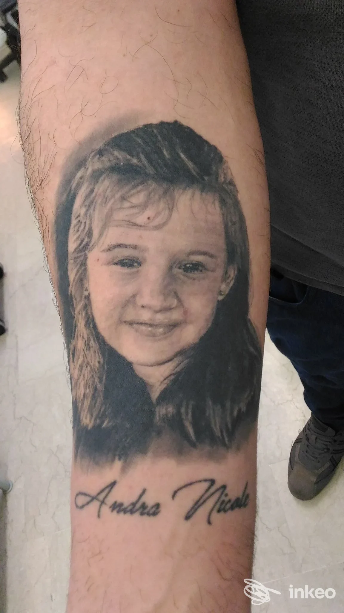 Ritratto tatuato in bianco e nero di una bambina sull'avambraccio, foto fornita da Ink Fever, Maerne.