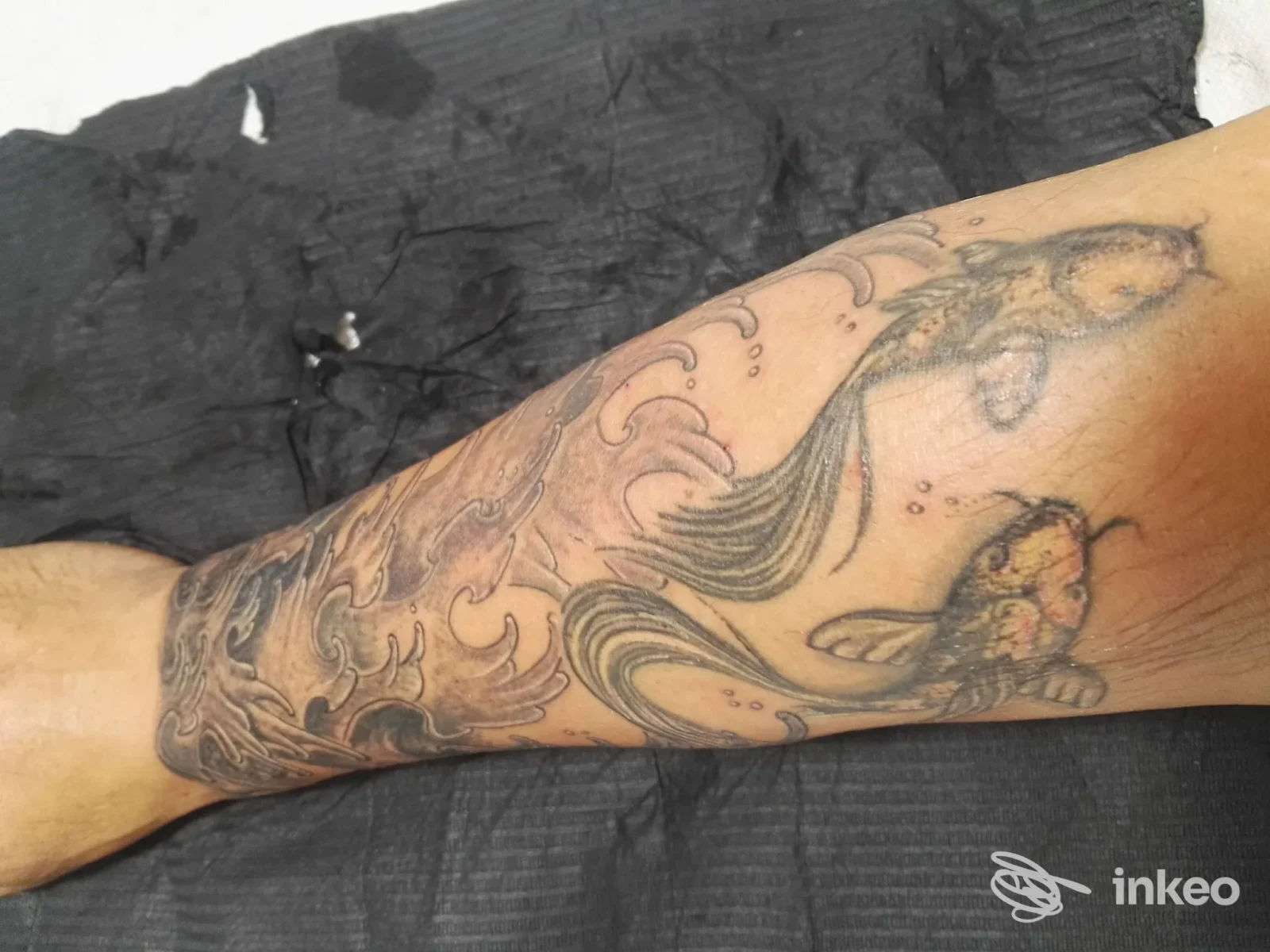 Tatuaggio di carpe koi e onde sull'avambraccio, foto per Metamorphose Studio Tattoo/Piercing a Cannigione.