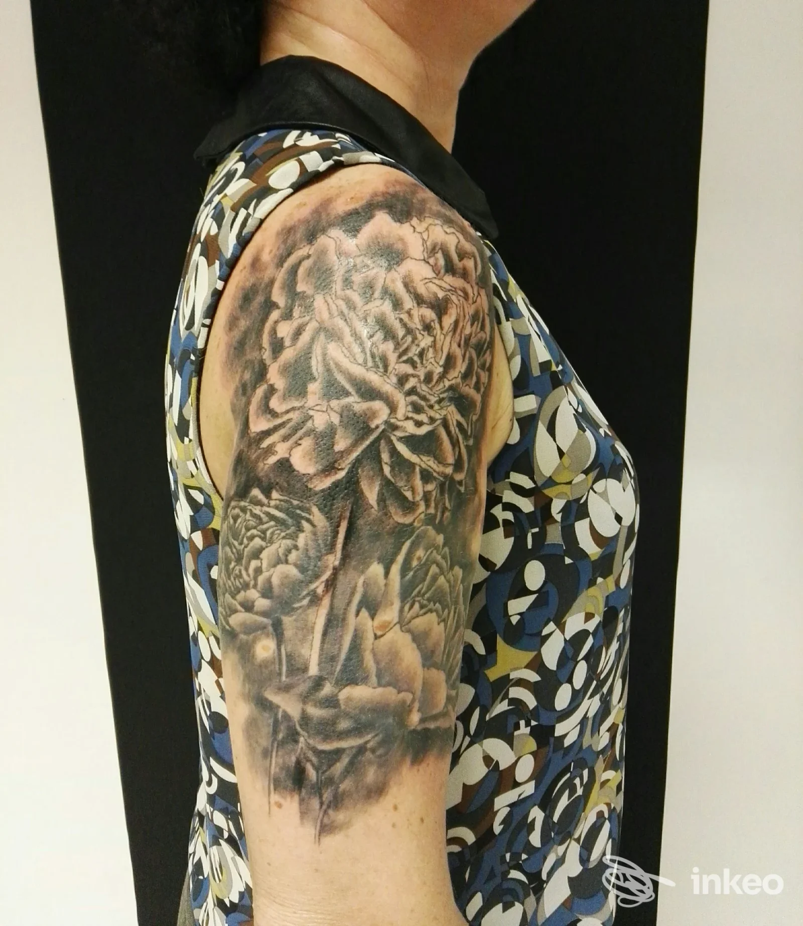 Ampio tatuaggio floreale in bianco e nero sulla spalla e braccio superiore, scatto realizzato per Al di là dello Specchio Tattoo Studio, Saccon.